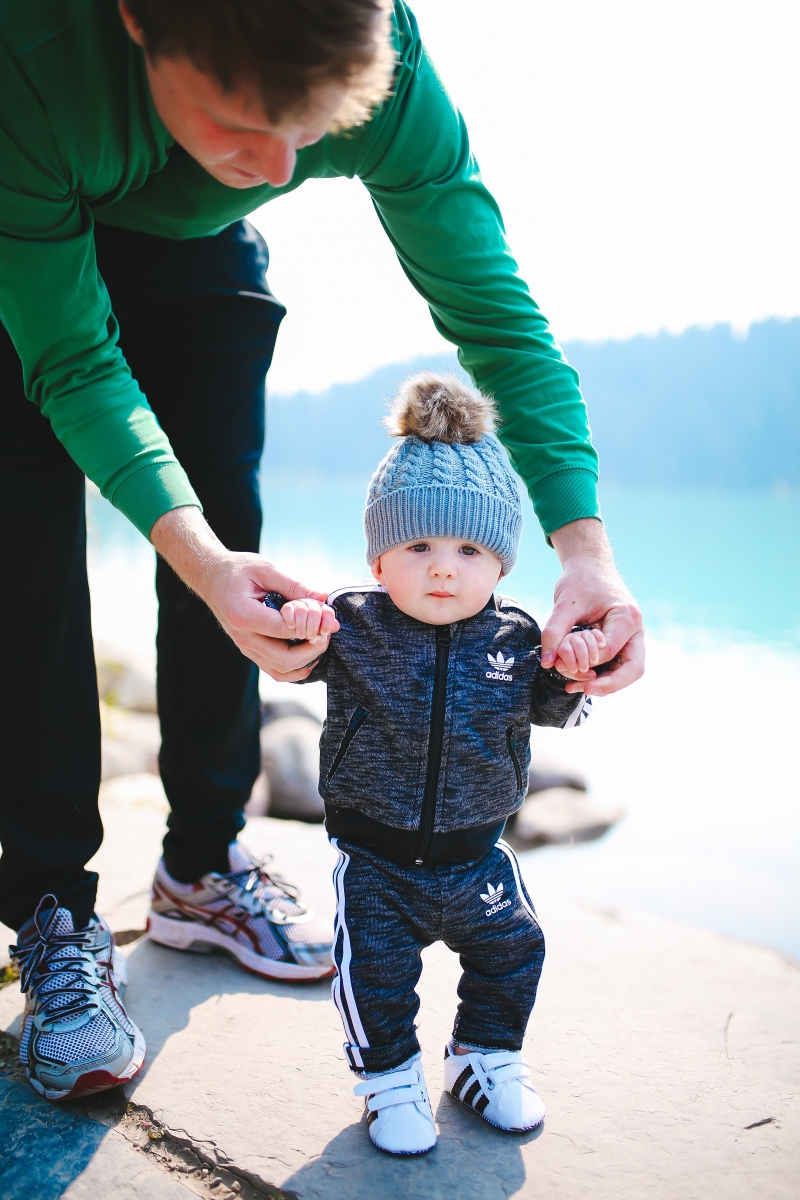 Baby boy fashion outfits, baby boy adidas tracksuit, baby boy adidas tennis shoes, baby boy mom matching adidas, lake louise canada, emily gemma blog, the sweetest thing blog, fall fashion pinterest tumblr, tumblr cute baby photos, pinterest cute baby photos, baby in beanies with puff balls, baby boy outfits winter time, travel bloggers with babies, the sweetest thing blog, adidas outfits fashion blogs, zella leggings | Cute Baby Boy Clothes by popular Michigan fashion blog, The Sweetest Thing: image of a baby wearing a Nordstrom Superstar Track Jacket & Pants Set ADIDAS ORIGINALS and Nordstrom Superstar Sneaker ADIDAS while his dad holds his hands and helps him walk. 