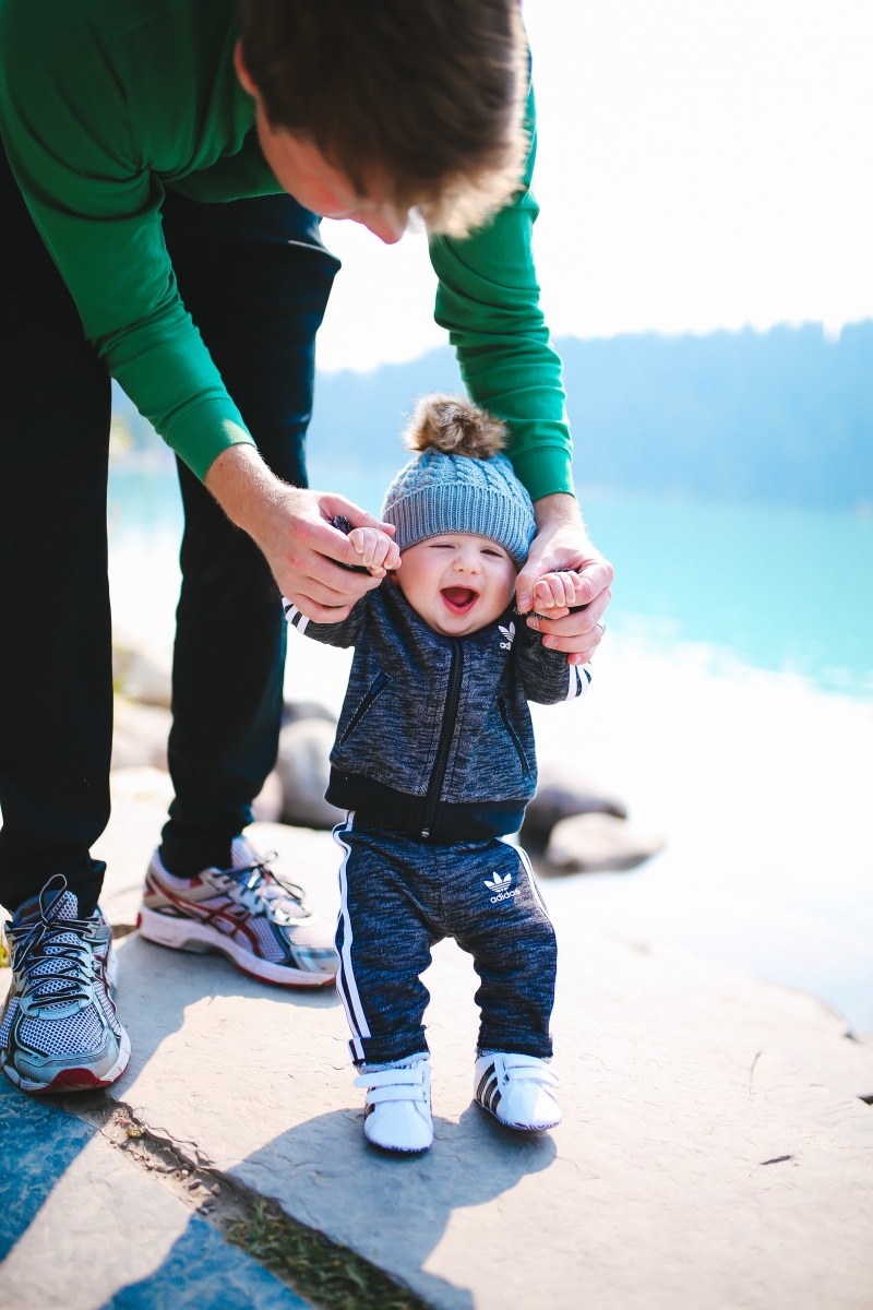 Baby boy fashion outfits, baby boy adidas tracksuit, baby boy adidas tennis shoes, baby boy mom matching adidas, lake louise canada, emily gemma blog, the sweetest thing blog, fall fashion pinterest tumblr, tumblr cute baby photos, pinterest cute baby photos, baby in beanies with puff balls, baby boy outfits winter time, travel bloggers with babies, the sweetest thing blog, adidas outfits fashion blogs, zella leggings | Cute Baby Boy Clothes by popular Michigan fashion blog, The Sweetest Thing: image of a baby wearing a Nordstrom Superstar Track Jacket & Pants Set ADIDAS ORIGINALS and Nordstrom Superstar Sneaker ADIDAS while his dad holds his hands and helps him walk. 