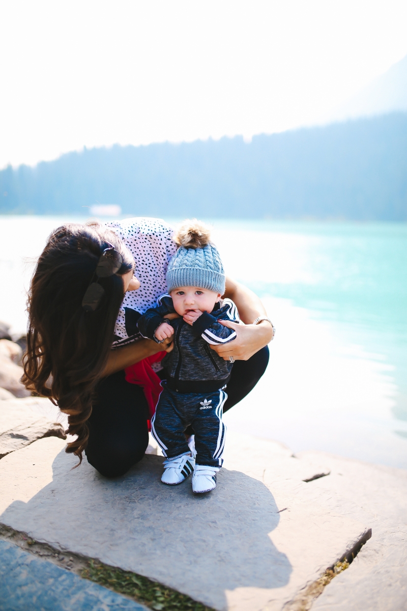 Baby boy fashion outfits, baby boy adidas tracksuit, baby boy adidas tennis shoes, baby boy mom matching adidas, lake louise canada, emily gemma blog, the sweetest thing blog, fall fashion pinterest tumblr, tumblr cute baby photos, pinterest cute baby photos, baby in beanies with puff balls, baby boy outfits winter time, travel bloggers with babies, the sweetest thing blog, adidas outfits fashion blogs, zella leggings | Cute Baby Boy Clothes by popular Michigan fashion blog, The Sweetest Thing: image of a mom holding her baby and wearing a Nordstrom Originals NMD Logo Tee ADIDAS, Nordstrom Superstar Sneaker ADIDAS, Nordstrom High Key 62mm Aviator Sunglasses QUAY AUSTRALIA, Nordstrom Deco Diamond Diamond Dial Watch Head, 33mm x 35mm MICHELE, Nordstrom Superstar Track Jacket & Pants Set ADIDAS ORIGINALS, and Nordstrom Superstar Sneaker ADIDAS.