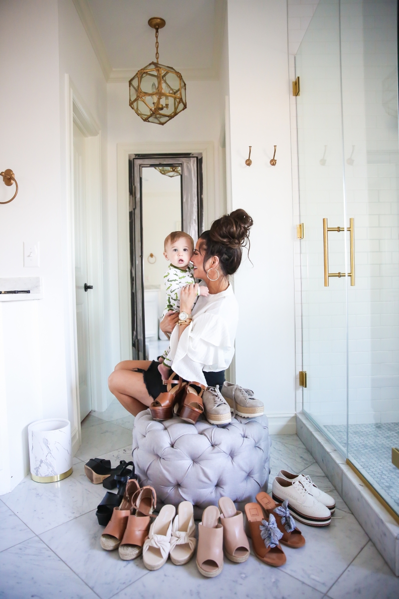 Cute Spring Shoes by popular US fashion blog, The Sweetest Thing: image of a mom holding her baby and sitting on a tufted ottoman next to various wedge sandals and platform loafers. 