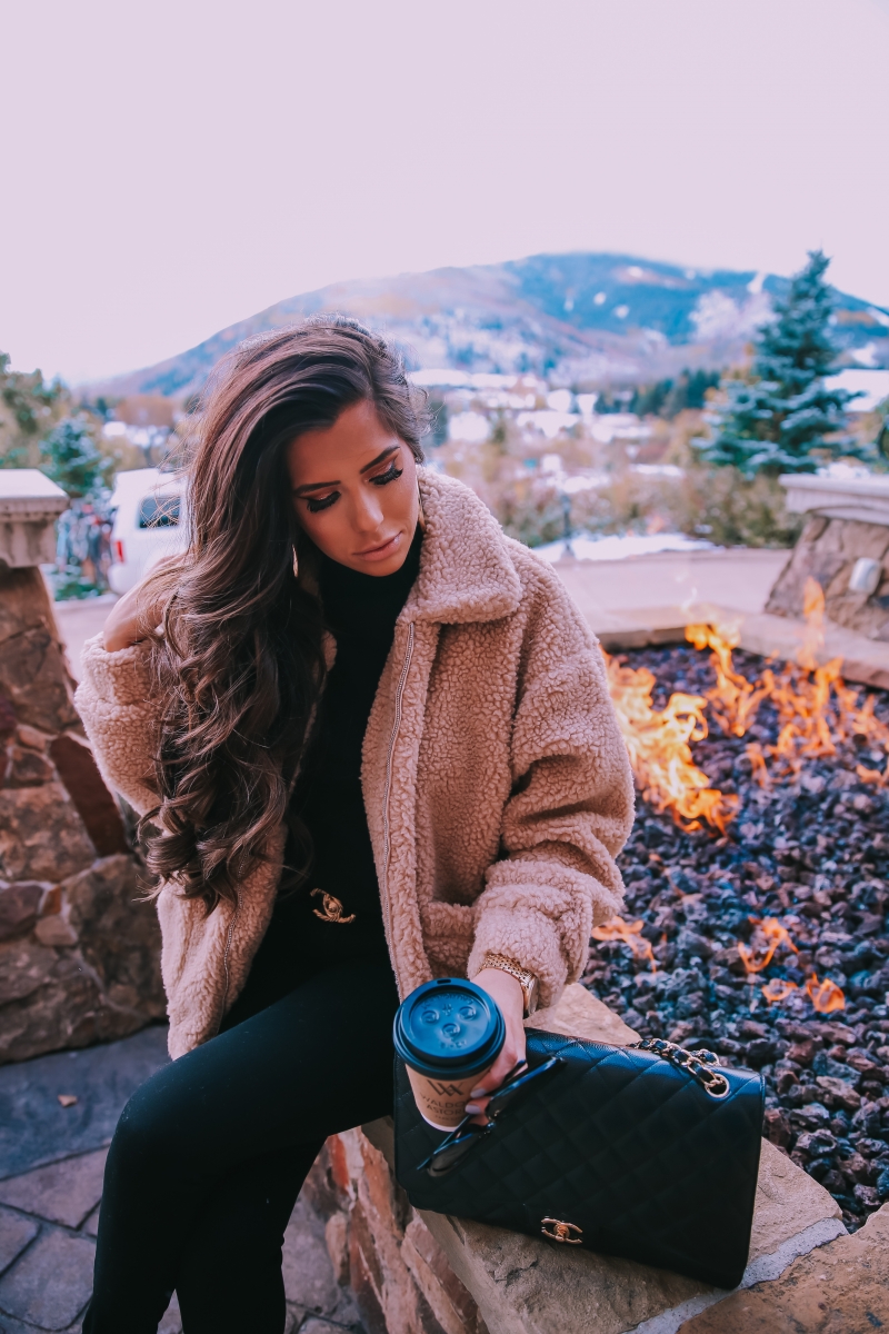 Fall fashion pinterest 2018, teddy bear coat outfit pinterest 2018, IAMGIA teddy coat, chanel belt outfit, park city travel fashion blogger, emily gemma blog, chanel classic black maxi-3 | I Am Gia Teddy Bear Jacket by popular US fashion blog, The Sweetest Thing: image of a woman standing outside next to a gas fire pit and wearing a Pixie Coat  I.AM.GIA brand: I.AM.GIA, H&M Ribbed Turtleneck Top, Nordstrom Florence Instasculpt Ankle Skinny Jeans DL1961, ShopBop Ash boots, H&M Large Earrings, Nordstrom Lip Cheat Lip Liner CHARLOTTE TILBURY, Chanel belt, Chanel purse, and Nordstrom MAC Matte Lipstick MAC COSMETICS.