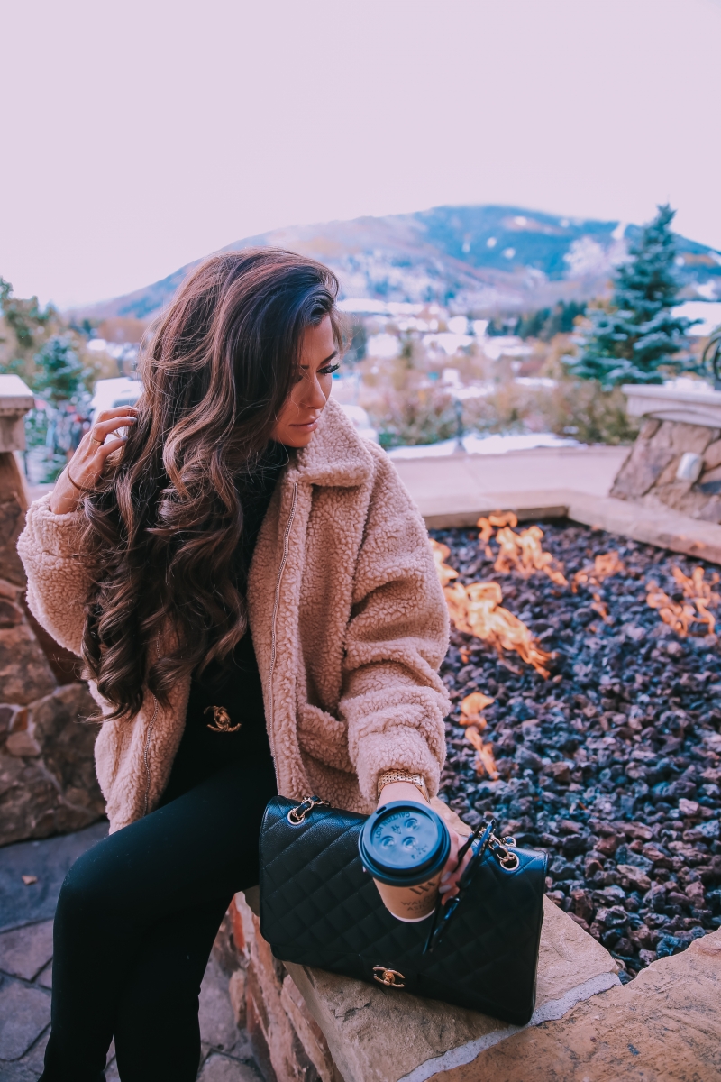 Fall fashion pinterest 2018, teddy bear coat outfit pinterest 2018, IAMGIA teddy coat, chanel belt outfit, park city travel fashion blogger, emily gemma blog, chanel classic black maxi-3 | I Am Gia Teddy Bear Jacket by popular US fashion blog, The Sweetest Thing: image of a woman standing outside next to a gas fire pit and wearing a Pixie Coat  I.AM.GIA brand: I.AM.GIA, H&M Ribbed Turtleneck Top, Nordstrom Florence Instasculpt Ankle Skinny Jeans DL1961, ShopBop Ash boots, H&M Large Earrings, Nordstrom Lip Cheat Lip Liner CHARLOTTE TILBURY, Chanel belt, Chanel purse, and Nordstrom MAC Matte Lipstick MAC COSMETICS.