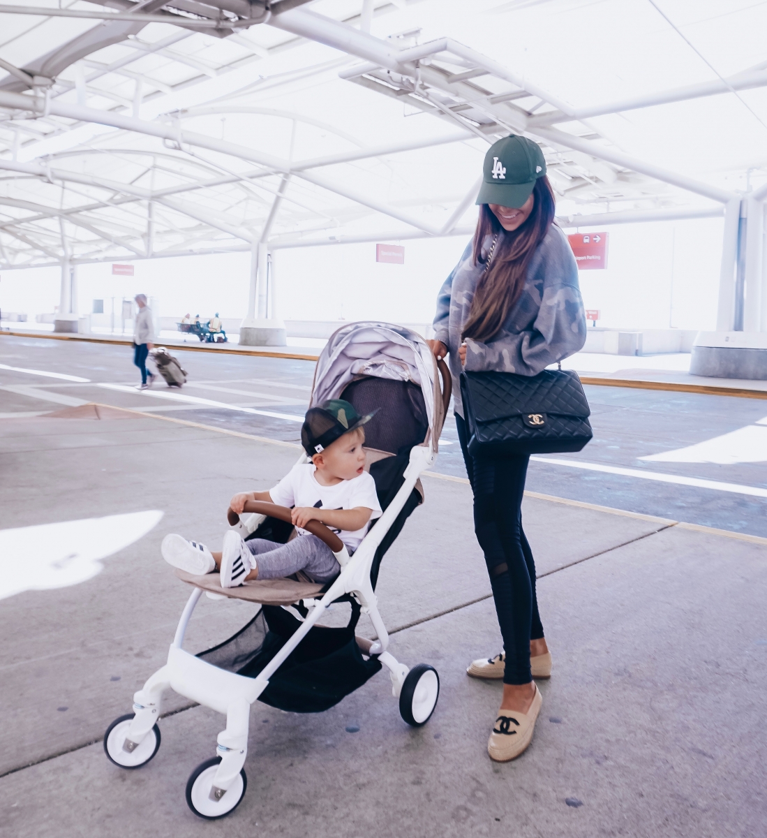 20 Easy To Re-Create Cute Travel Outfits featured by top US fashion and travel blogger, Emily Gemma of The Sweetest Thing: pinterest cute airport travel fashion outfit fall 2018, emily gemma travel style, stylish cute casual travel outfit idea 2018, travel stroller baby sing amazon, camo sweatshirt leggings travel outfit