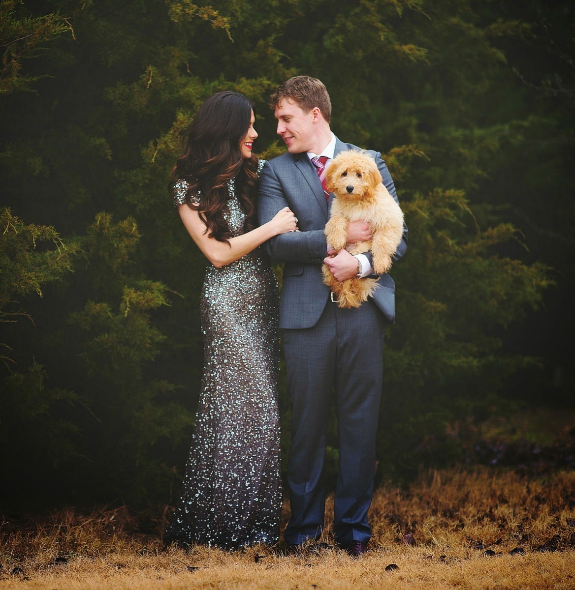 Sequin Leggings Outfit by popular US fashion blog, The Sweetest Thing: image of a woman wearing a silver sequin dress and standing next to her husband who is wearing a suit and holding their goldendoodle puppy. 