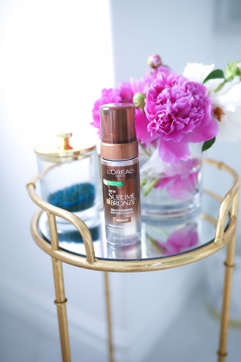 Emily Ann Gemma of The Sweetest Thing Blog L’OREAL SUBLIME BRONZE SELF TANNING WATER MOUSSE review | Loreal Water Mousse by popular US beauty blog, The Sweetest Thing: image of a Loreal water mousse self tanner next to a vase of peonies. 