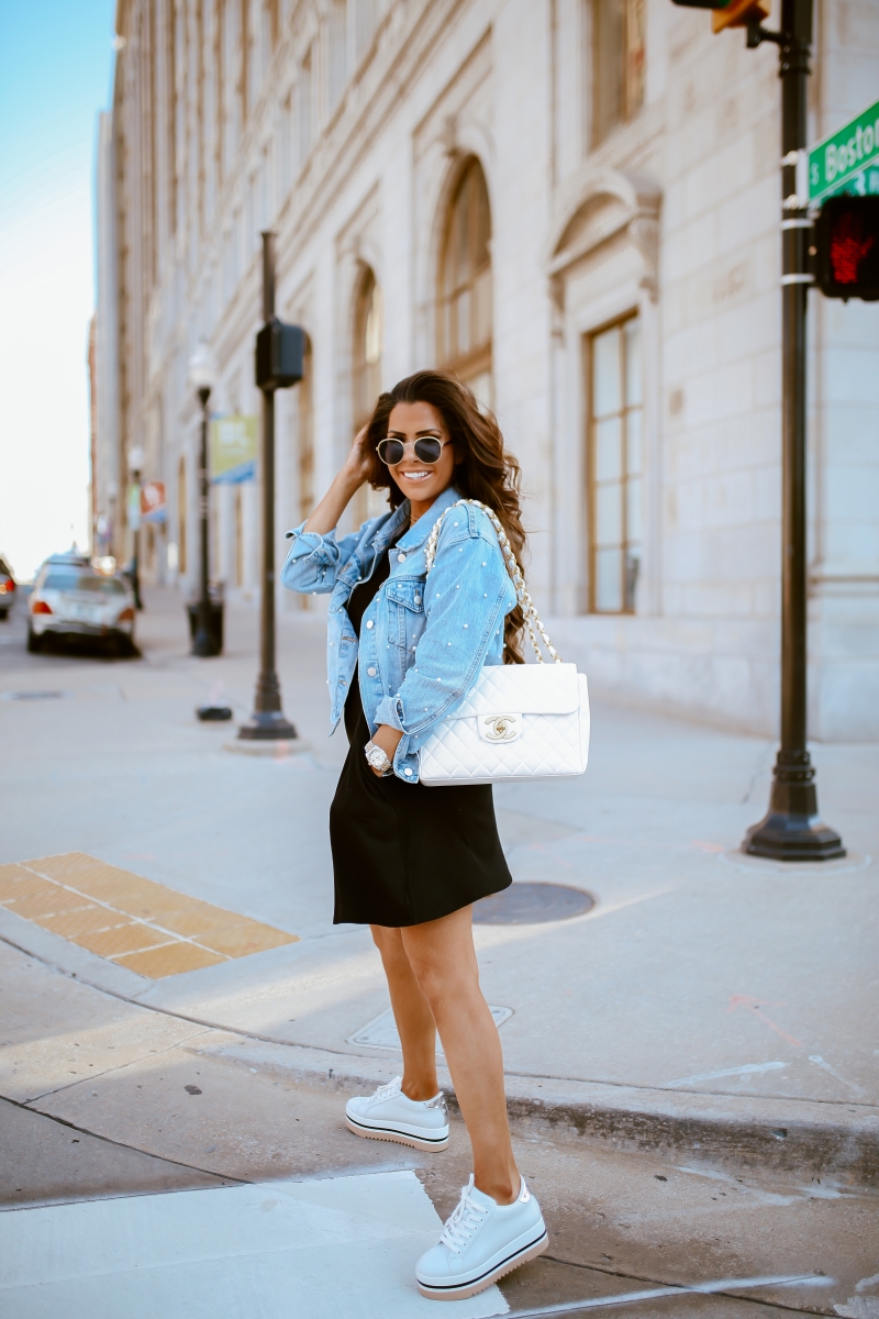 Emily Ann Gemma of The Sweetest Thing Blog in an under $40 black dress, pearl embellished denim jacket, white Chanel handbag, and platform tennis shoes from Steve Madden.
