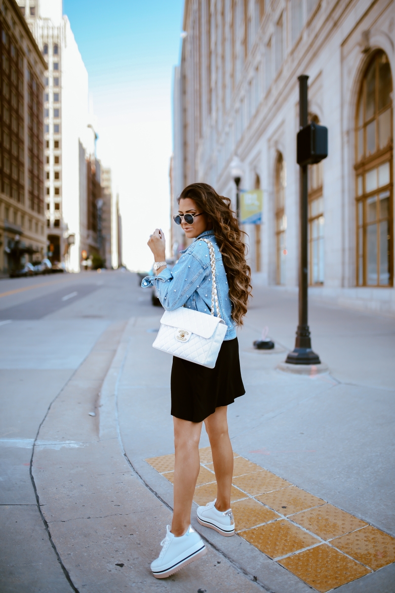 Emily Ann Gemma of The Sweetest Thing Blog in an under $40 black dress, pearl embellished denim jacket, white Chanel handbag, and platform tennis shoes from Steve Madden.