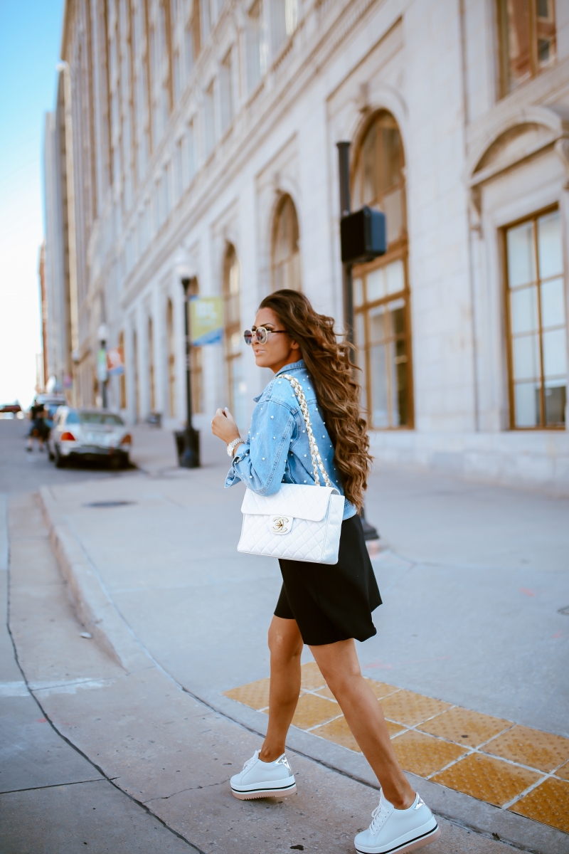 Emily Ann Gemma of The Sweetest Thing Blog in an under $40 black dress, pearl embellished denim jacket, white Chanel handbag, and platform tennis shoes from Steve Madden.