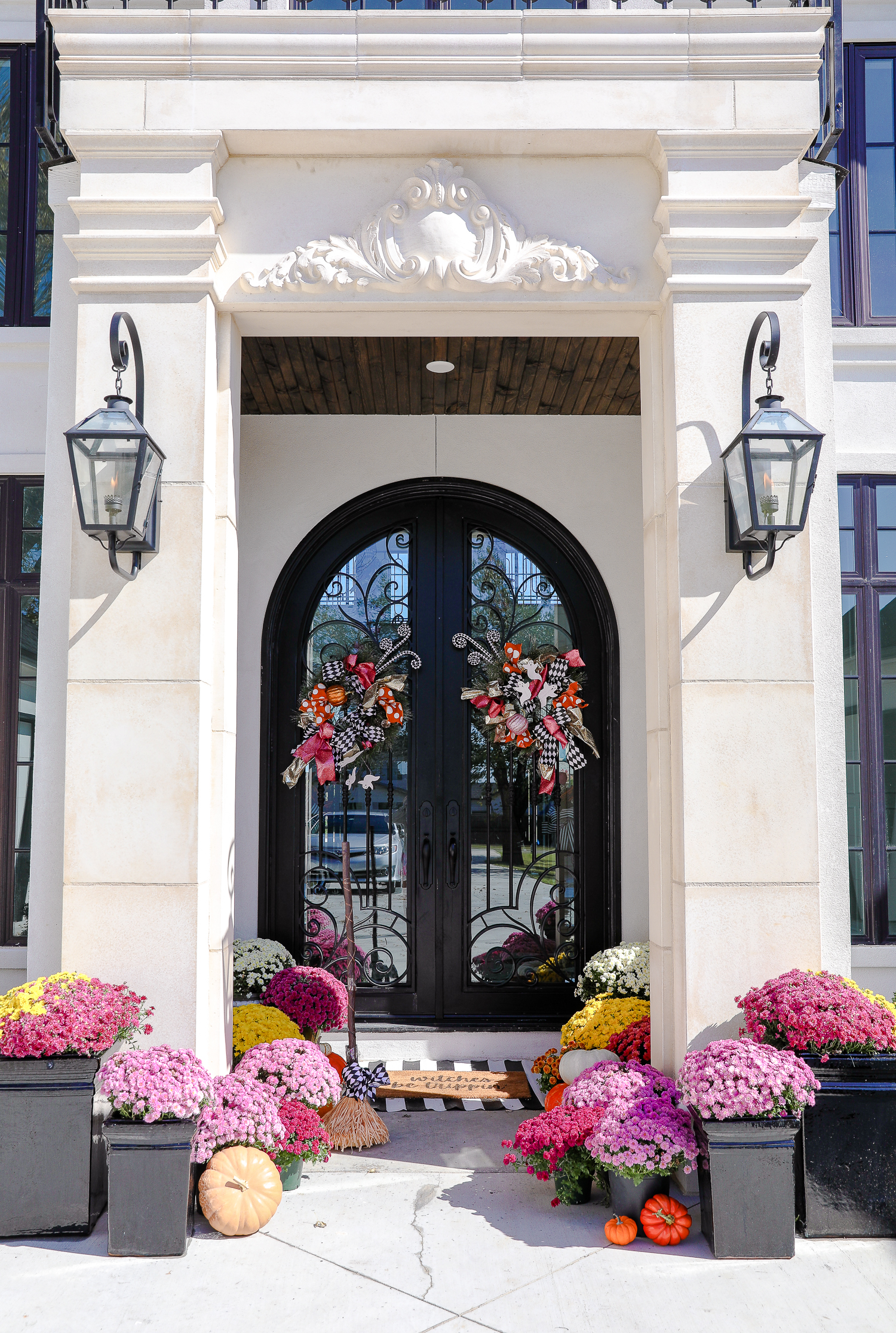 pink mums, front door decor striped rug, pink mums, fall halloween decor, shop hello holidays, emily gemma | Fall & Halloween Home Decor Tour by popular Oklahoma life and style blog, The Sweetest Thing: image of the front entrance to a home decorated with pink mums, pumpkins, a black and white stripe rug, and a welcome mat.