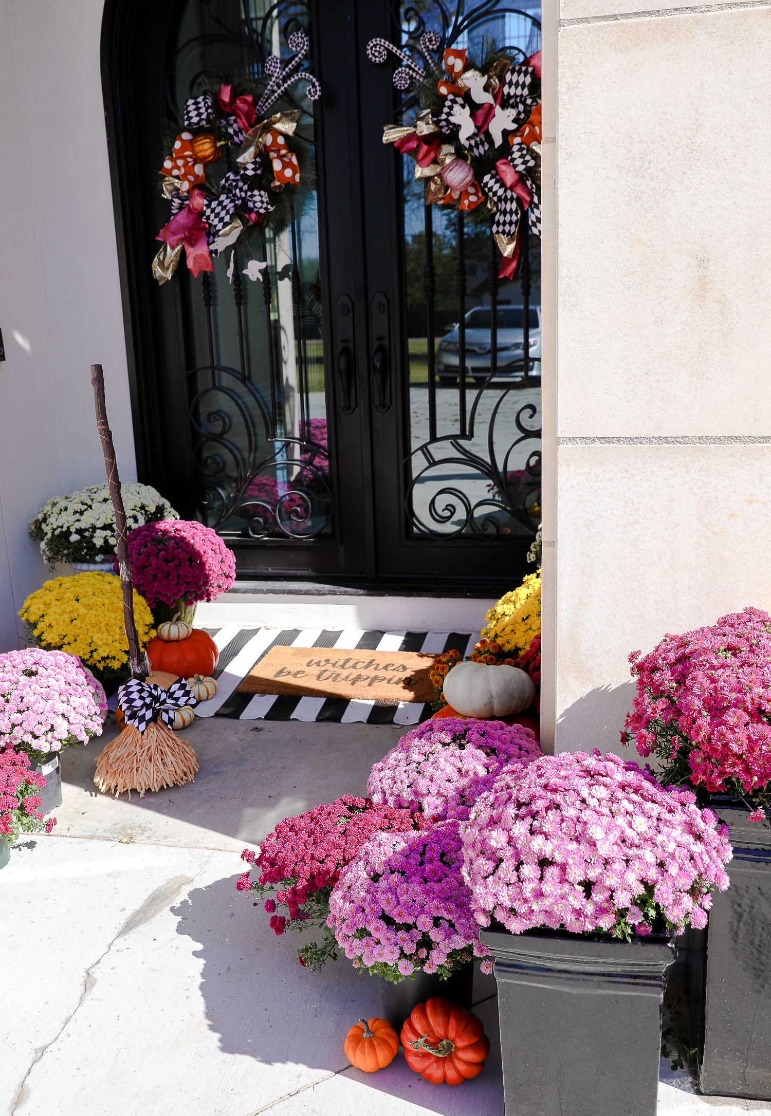 pink mums, front door decor striped rug, pink mums, fall halloween decor, shop hello holidays, emily gemma | Fall & Halloween Home Decor Tour by popular Oklahoma life and style blog, The Sweetest Thing: image of the front entrance to a home decorated with pink mums, pumpkins, a black and white stripe rug, and a welcome mat.