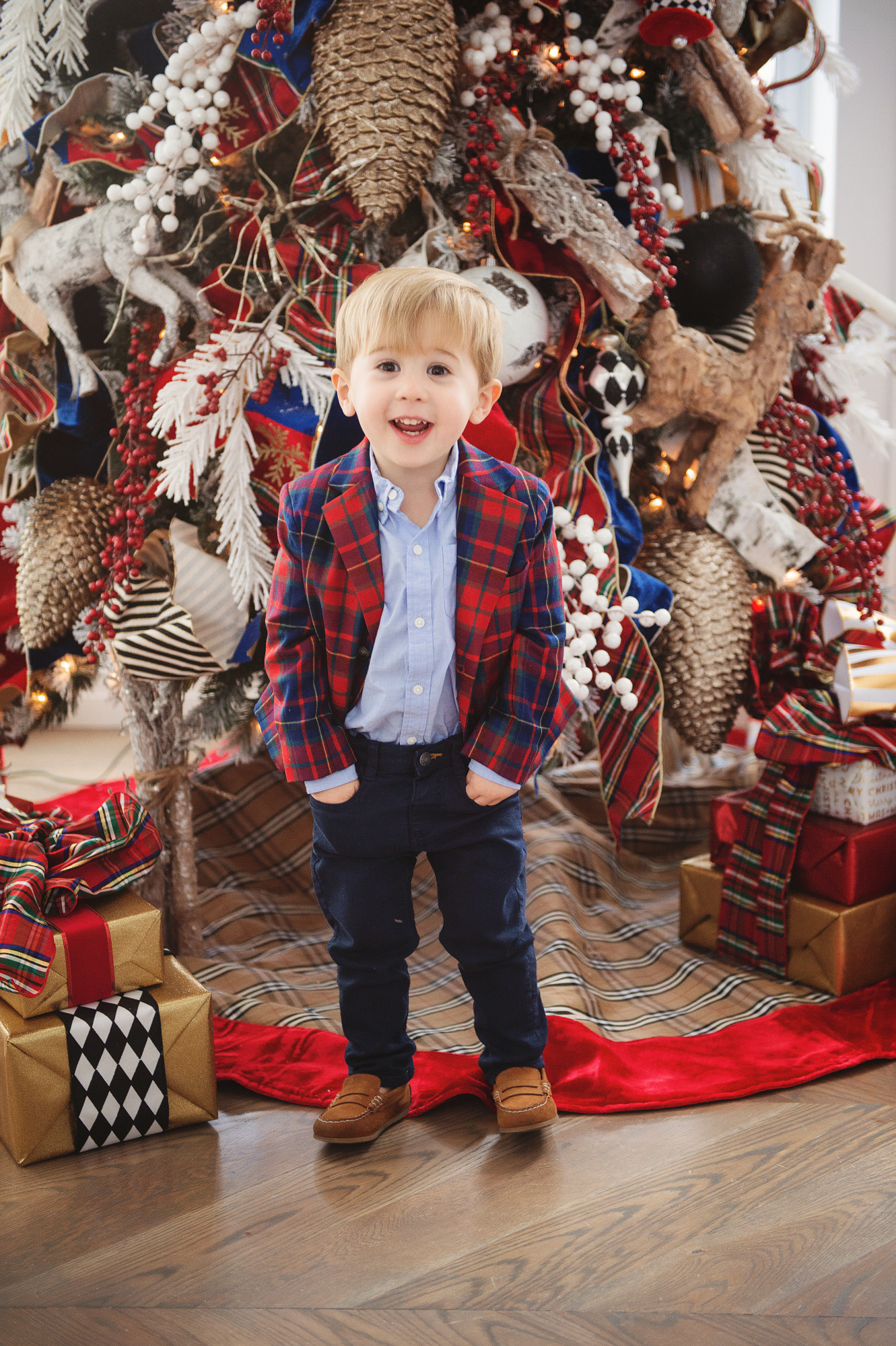 family Christmas card outfit inspiration, smocked Christmas dress baby, baby boy fashion Christmas, pinterest Christmas tree decor, shop hello holidays, Emily Gemma, the sweetest thing blog | Merry Christmas Wishes To You & Yours🎁❤️🎄 [Our Christmas Card 2019] by popular Oklahoma life and style blog, The Sweetest Thing: image of a little boy sitting in front of their Christmas tree and wearing Zara BASIC SERGED SKINNY JEANS, Zara  LEATHER LOAFERS, Janie and Jack POPLIN SHIRT, Janie and Jack PLAID WOOL BLAZER.