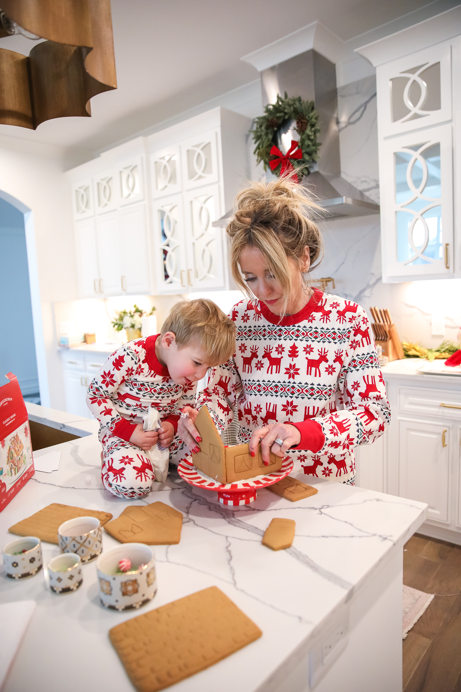 Hanna Anderson pjs christmas, family matching christmas pajamas, christmas decor pajamas 2019 pinterest, babies christmas pajamas matching, the sweetest thing blog-5 | Coco & Crew In Matching Hanna Andersson Christmas Pajamas by popular Oklahoma life and style blog, The Sweetest Thing: image of a family decorating gingerbread houses and wearing Hanna Andersson Long John Pajamas In Organic Cotton, Hanna Andersson Adult Long John Pant In Organic Cotton, Hanna Andersson Women's Long John Top In Organic Cotton, Hanna Andersson Adult Long John Top In Organic Cotton, and Hanna Andersson Adult Long John Pant In Organic Cotton.