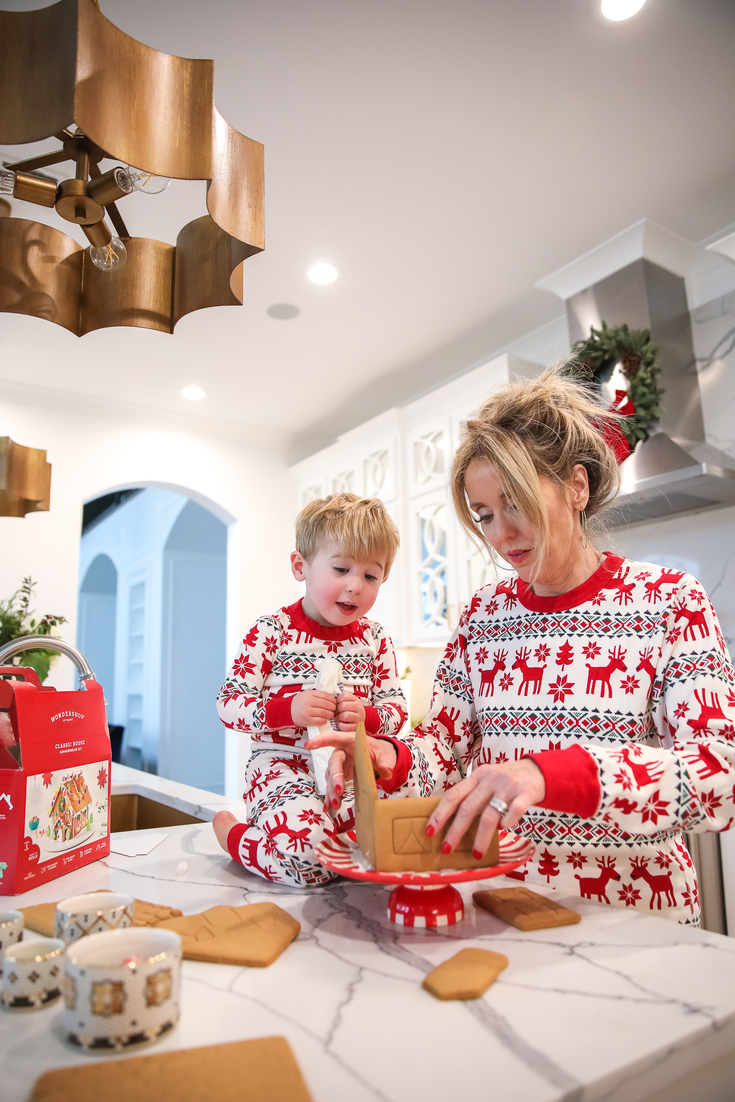 Hanna Anderson pjs christmas, family matching christmas pajamas, christmas decor pajamas 2019 pinterest, babies christmas pajamas matching, the sweetest thing blog-5 | Coco & Crew In Matching Hanna Andersson Christmas Pajamas by popular Oklahoma life and style blog, The Sweetest Thing: image of a family decorating gingerbread houses and wearing Hanna Andersson Long John Pajamas In Organic Cotton, Hanna Andersson Adult Long John Pant In Organic Cotton, Hanna Andersson Women's Long John Top In Organic Cotton, Hanna Andersson Adult Long John Top In Organic Cotton, and Hanna Andersson Adult Long John Pant In Organic Cotton.