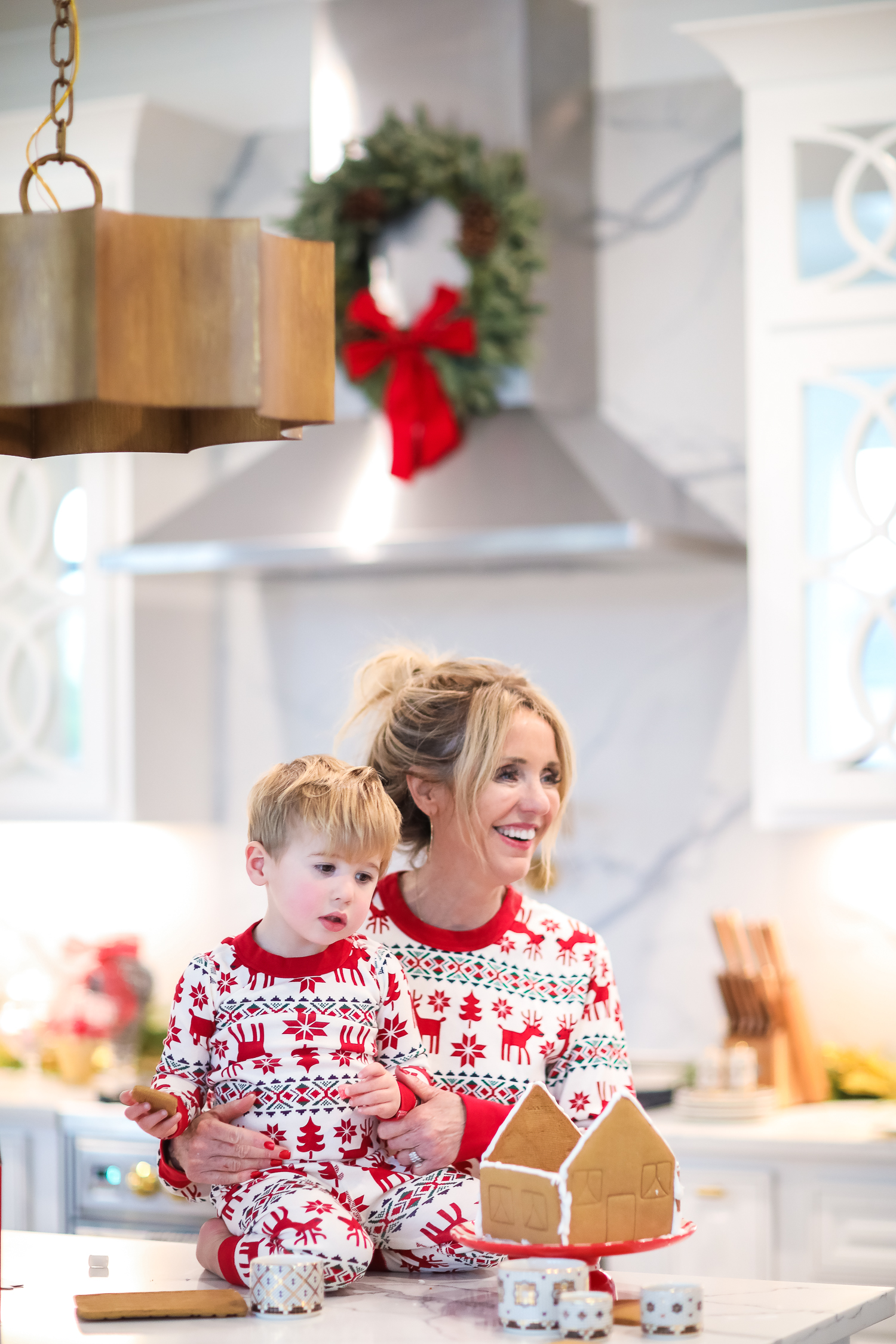 Hanna Anderson pjs christmas, family matching christmas pajamas, christmas decor pajamas 2019 pinterest, babies christmas pajamas matching, the sweetest thing blog-5 | Coco & Crew In Matching Hanna Andersson Christmas Pajamas by popular Oklahoma life and style blog, The Sweetest Thing: image of a family decorating gingerbread houses and wearing Hanna Andersson Long John Pajamas In Organic Cotton, Hanna Andersson Adult Long John Pant In Organic Cotton, Hanna Andersson Women's Long John Top In Organic Cotton, Hanna Andersson Adult Long John Top In Organic Cotton, and Hanna Andersson Adult Long John Pant In Organic Cotton.