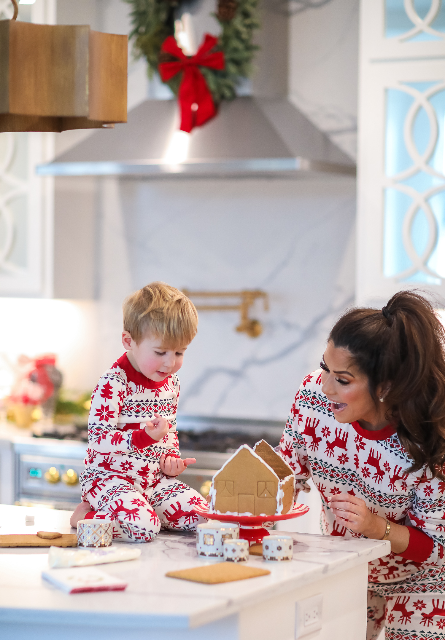 Hanna Anderson pjs christmas, family matching christmas pajamas, christmas decor pajamas 2019 pinterest, babies christmas pajamas matching, the sweetest thing blog-5 | Coco & Crew In Matching Hanna Andersson Christmas Pajamas by popular Oklahoma life and style blog, The Sweetest Thing: image of a family decorating gingerbread houses and wearing Hanna Andersson Long John Pajamas In Organic Cotton, Hanna Andersson Adult Long John Pant In Organic Cotton, Hanna Andersson Women's Long John Top In Organic Cotton, Hanna Andersson Adult Long John Top In Organic Cotton, and Hanna Andersson Adult Long John Pant In Organic Cotton.