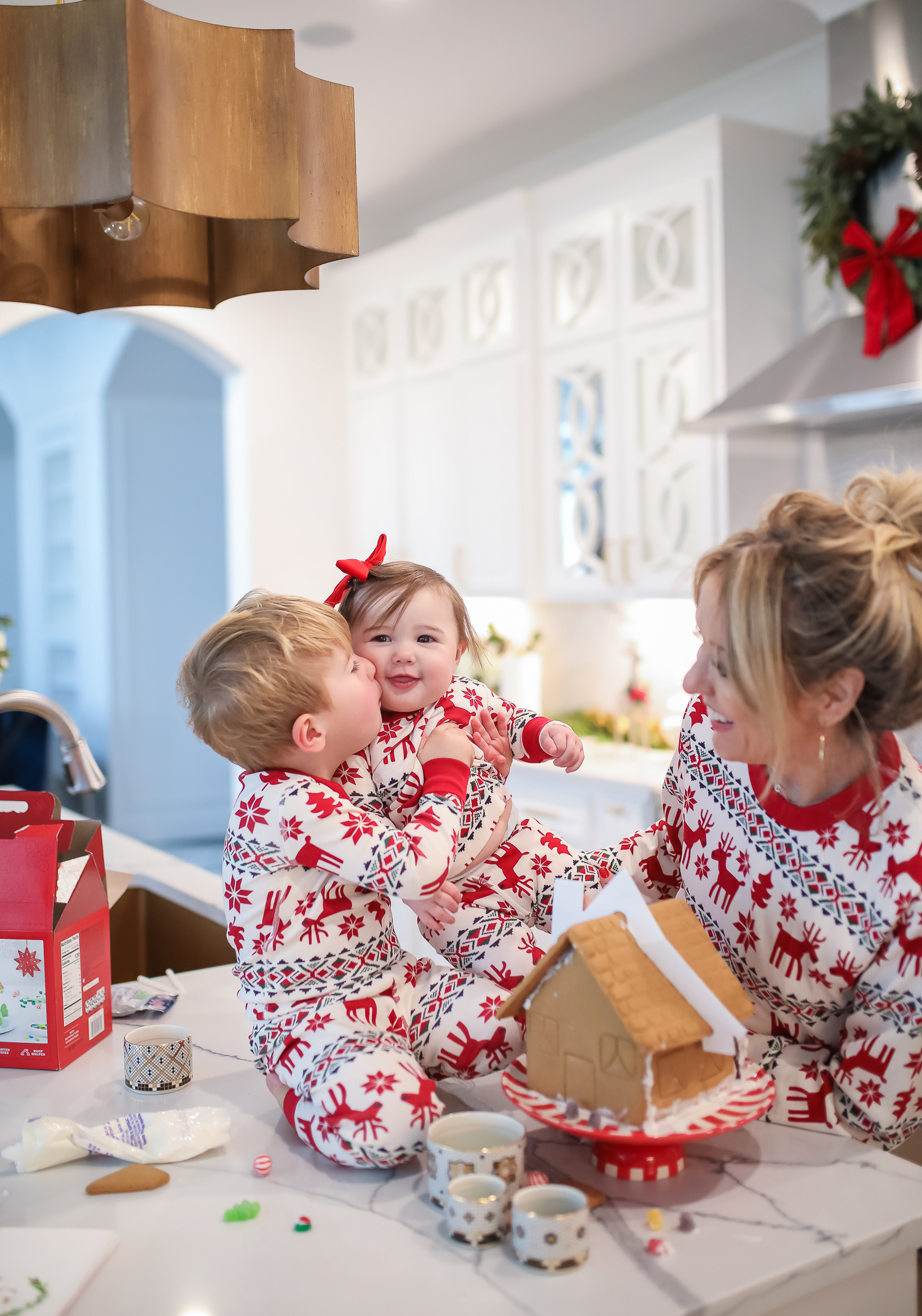 Hanna Anderson pjs christmas, family matching christmas pajamas, christmas decor pajamas 2019 pinterest, babies christmas pajamas matching, the sweetest thing blog-5 | Coco & Crew In Matching Hanna Andersson Christmas Pajamas by popular Oklahoma life and style blog, The Sweetest Thing: image of a family decorating gingerbread houses and wearing Hanna Andersson Long John Pajamas In Organic Cotton, Hanna Andersson Adult Long John Pant In Organic Cotton, Hanna Andersson Women's Long John Top In Organic Cotton, Hanna Andersson Adult Long John Top In Organic Cotton, and Hanna Andersson Adult Long John Pant In Organic Cotton.