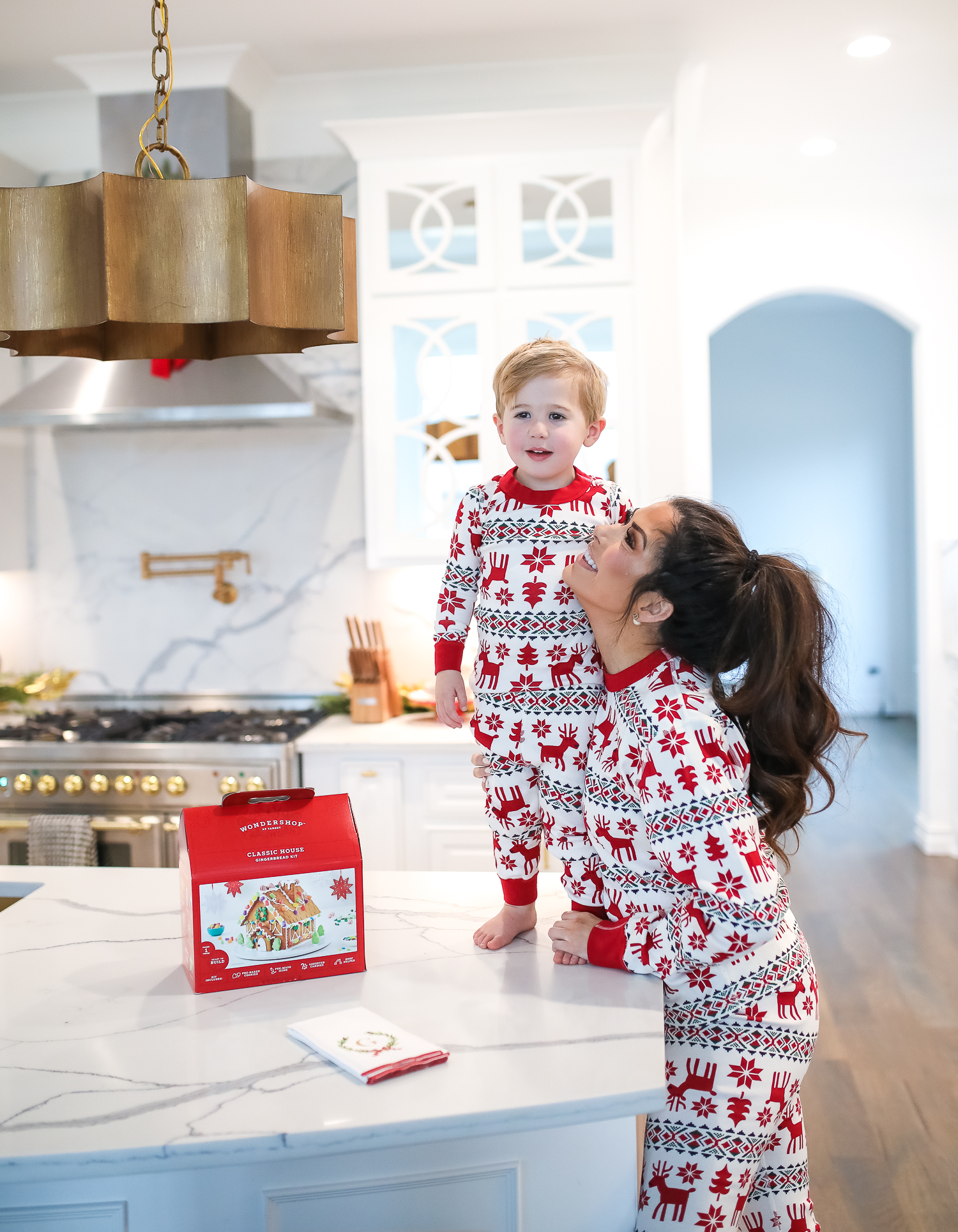 Hanna Anderson pjs christmas, family matching christmas pajamas, christmas decor pajamas 2019 pinterest, babies christmas pajamas matching, the sweetest thing blog-5 | Coco & Crew In Matching Hanna Andersson Christmas Pajamas by popular Oklahoma life and style blog, The Sweetest Thing: image of a family decorating gingerbread houses and wearing Hanna Andersson Long John Pajamas In Organic Cotton, Hanna Andersson Adult Long John Pant In Organic Cotton, Hanna Andersson Women's Long John Top In Organic Cotton, Hanna Andersson Adult Long John Top In Organic Cotton, and Hanna Andersson Adult Long John Pant In Organic Cotton.