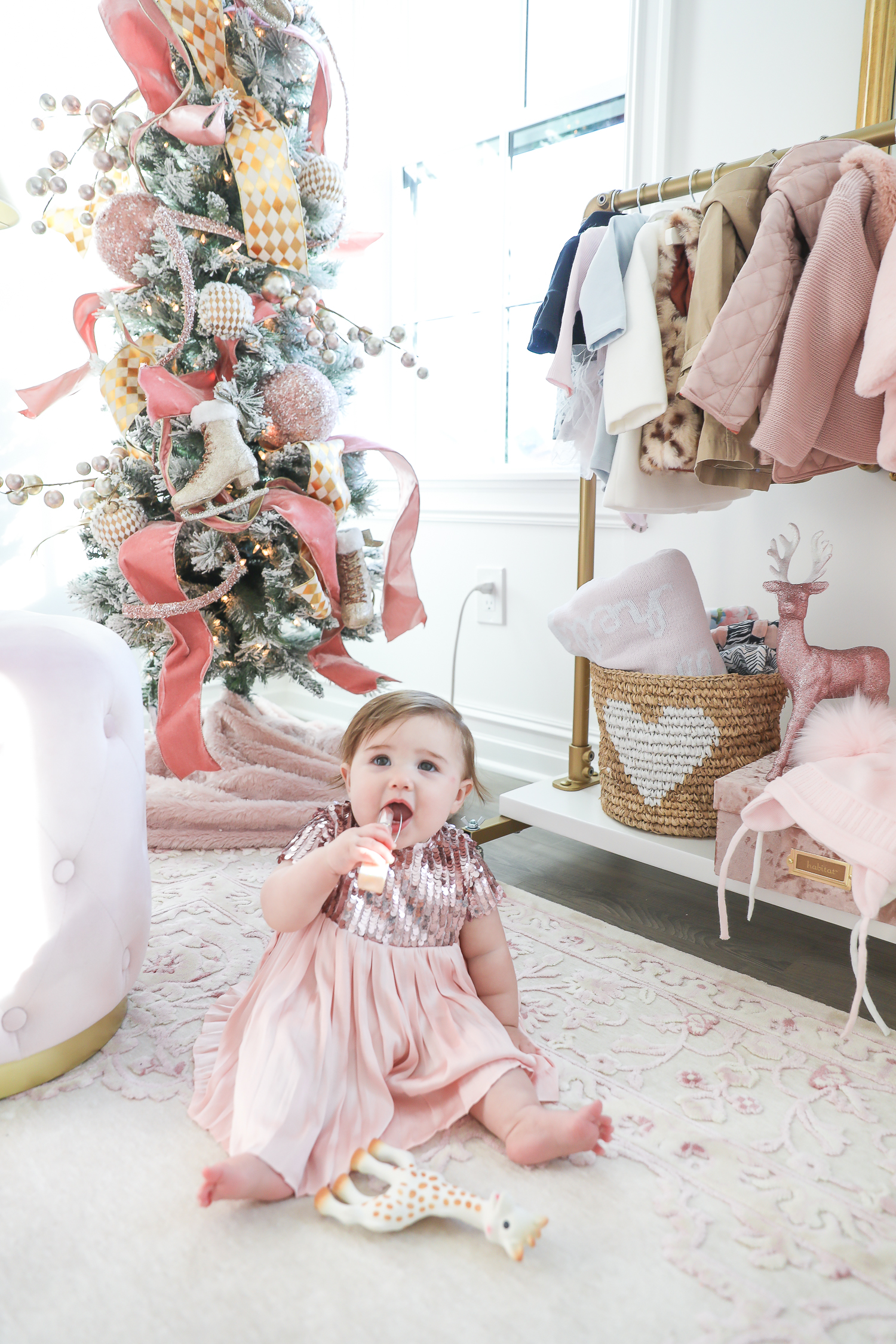 baby girl nursery inspiration christmas pinterest, baby girl nursery christmas tree, emily gemma, gold baby garment rack, the sweetest thing blog-2 |  Sophia’s Baby Girl Nursery at Christmastime by popular Oklahoma life and style blog, The Sweetest Thing: image of a girl nursery decorated with a Nordstrom Nolene Sequin Party Dress, Pottery Barn Kids Merced Glider & Ottoman, Wayfair Piper 2-in-1 Convertible Crib, RH Baby & Child NEW RUFFLE APPLIQUÉD ORGANIC VOILE NURSERY BEDDING COLLECTION, Wayfair Fontanne Oriental Pink/White Area Rug, Overstock Clover 8-light Aged Brass Chandelier, Horchow Sophia Rectangular Dressing Mirror, Etsy ShopAndisList Childrens standard rack, Pottery Barn Kids Raffia Heart Baskets, RH Baby & Child GILT DEMILUNE CANOPY BED CROWN, Walmart Holiday Time Pre-Lit Snow-Flocked Colorado Artificial Christmas Tree, 7', White Lights, Target Wondershop Glitter Deer Decorative Figurine Blush, T.J. Maxx pink velvet storage box, Wayfair Arnulfo 6 Drawer Double Dresser, Nordstrom Nursery Essential Gift Set, Nordstrom Sophie la Girafe Teething Toy, Glamboxes GLAMstand Hair Accessory Organizer, Serena & Lily Jenn Thatcher painting, Pottery Barn Kids Luxe Chamois Changing Pad, Crate & Kids Acrylic Shelf Bookcase, RH Baby and Child ANTIQUED GILT WOOD LETTER, Wayfair Luxe Solid Faux Fur Throw Pillow, Gap Toddler Cable-Knit Pom Beanie, Maisonette SteamLine Luggage *Exclusive* Vanity Case, Smocked Auctions NUTCRACKER SMOCKED BISHOP PINK GINGHAM, Nordstrom Ugg Jesse Bow Fluff Bootie, Overstock Safavieh Couture Carnation Round Tufted Ottoman, Pottery Barn Kids Blush Velvet Nursery Storage, and Nordstrom Chenille Blanket.