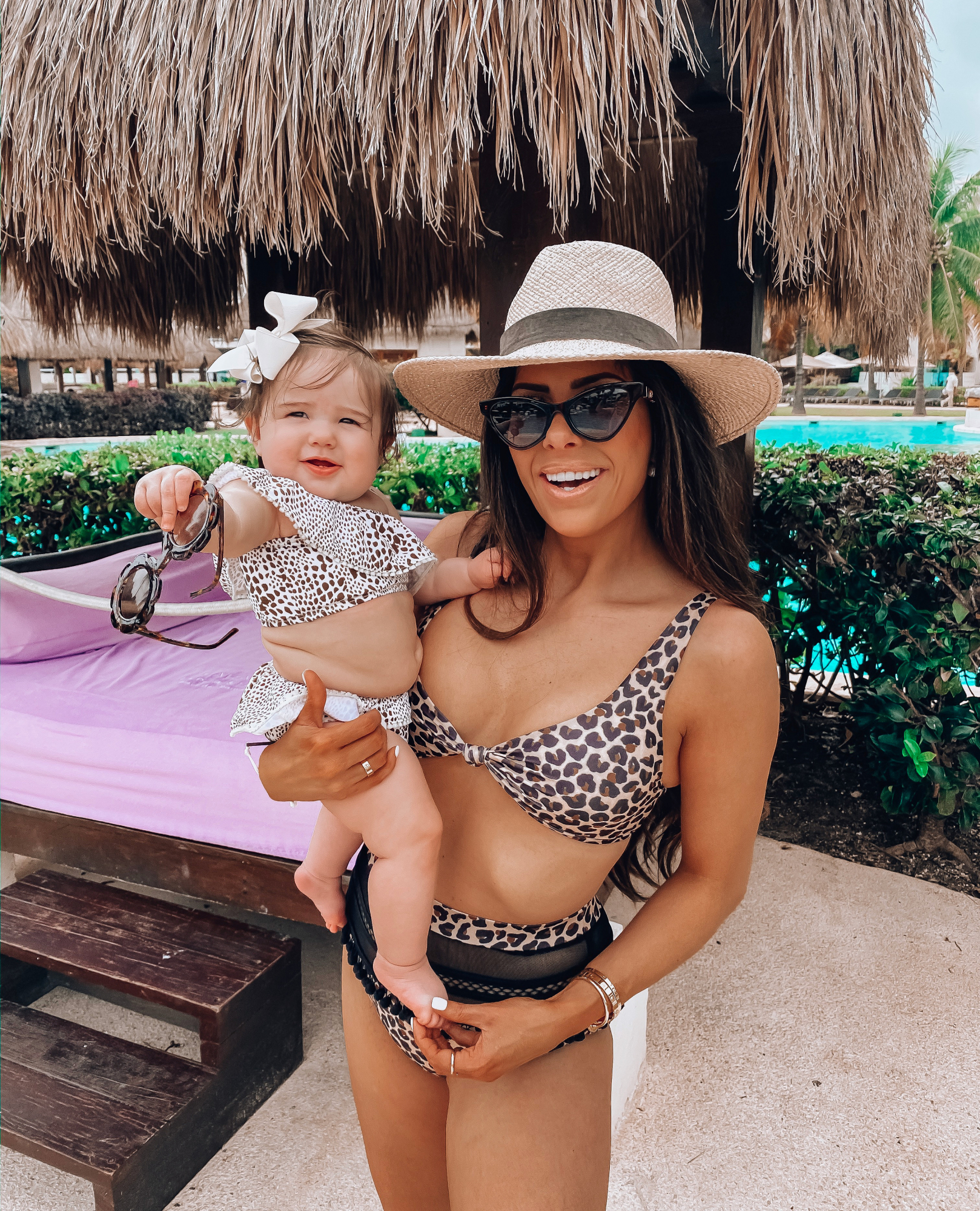 tularosa swimsuit review, janessa leone hat, gucci cay eye sunglasses | A YEAR IN REVIEW : MASSIVE 2019 INSTAGRAM RECAP by popular Oklahoma life and style blog, The Sweetest Thing: image of a mom holding her baby by the pool in Cancun, Mexico and wearing a leopard print bikini. 