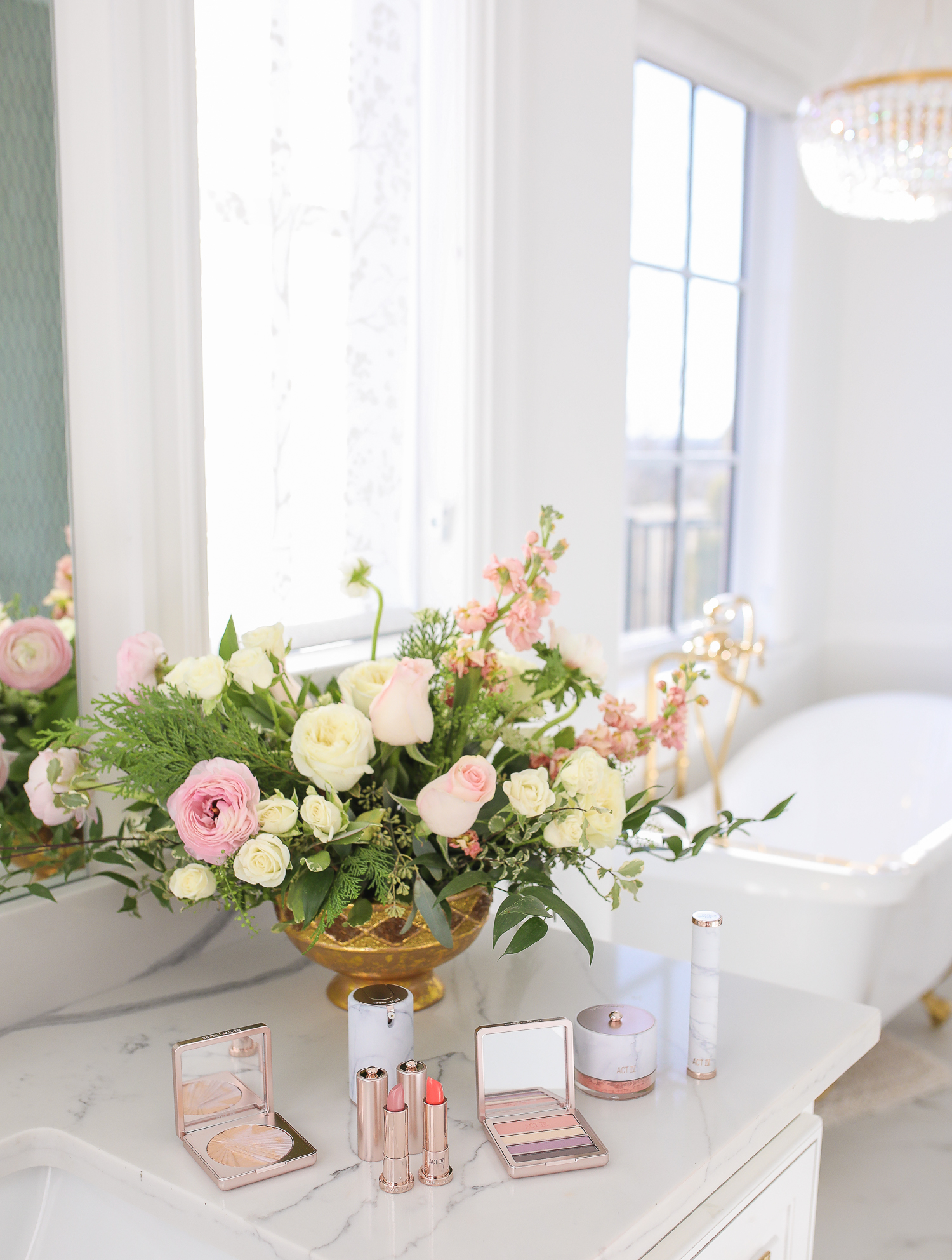 Estee Lauder Makeup by popular US beauty blog, The Sweetest Thing: image of various Estee Lauder Act IV makeup products on a bathroom counter next to a vase of flowers. 