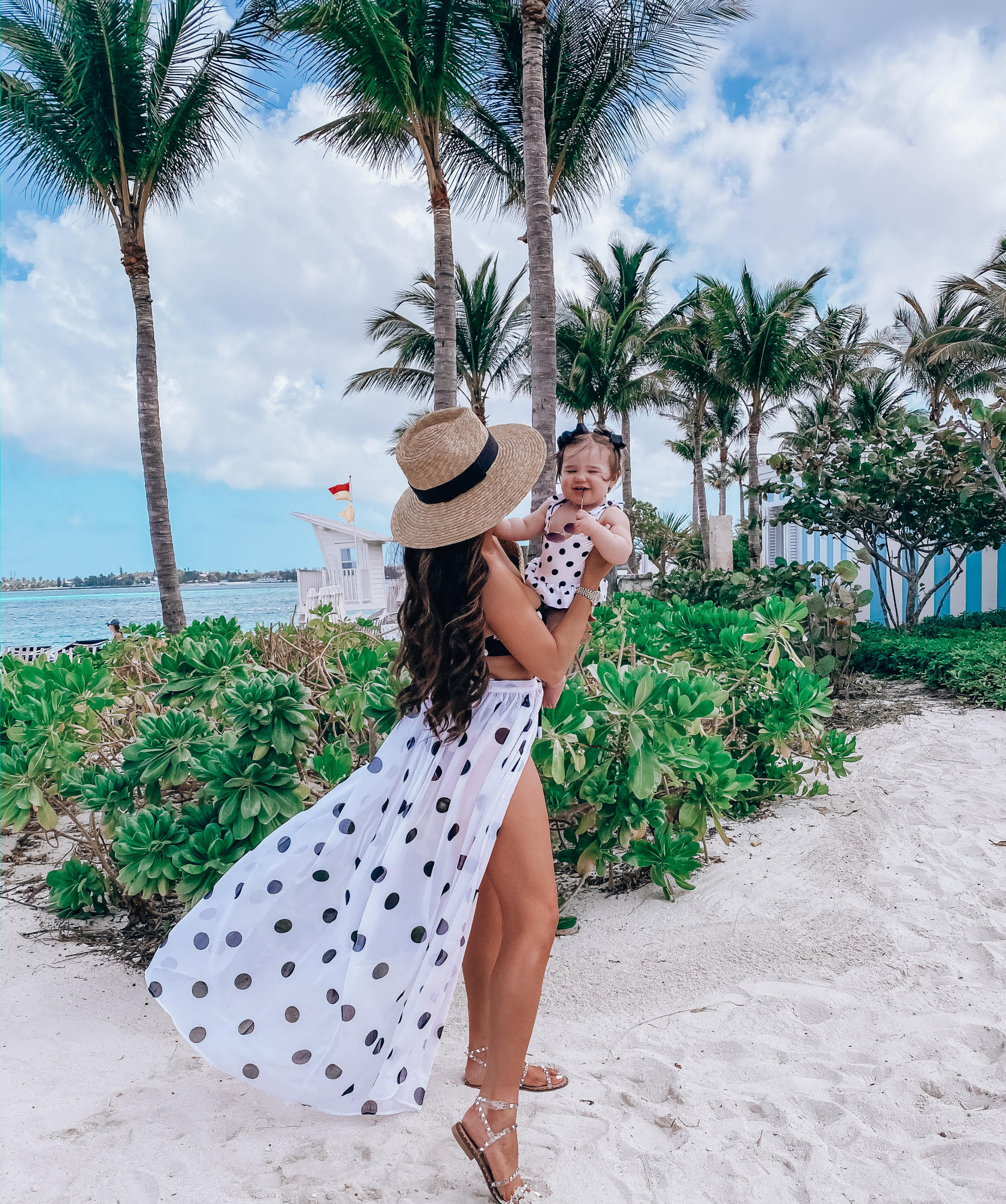 mara hoffman polkadot swimsuit, mother daughter fashionista, pinterest swimsuits 20205 | What to Wear in the Bahamas by popular US fashion blog, The Sweetest Thing: image of a woman holding her baby on the beach and wearing a MARA HOFFMAN Abigail Bandeau Bikini Top, MARA HOFFMAN Goldie High-Waist Bikini Bottoms, Nasty Gal I'm Dot Shady Cover-Up Maxi Skirt, Dior DiorSociety2 Round Beaded Metal Sunglasses, Steve Madden TRAVEL CLEAR, Nordstrom Joanna Straw Hat BRIXTON, ShopBop Hat Attack Round Handle Bag, Maisonette Snapper Rock Black & White Spot Skirt Swimsuit, Amazon Korobeauty Hair Bows Baby Girls, Amazon Roll over image to zoom in SA106 Kids Child Size Hippie Round Circle Lens Tie Dye Gradient Metal Sunglasses, Nordstrom Pillow Talk Lip Cheat Lip Liner CHARLOTTE TILBURY, Nordstrom Hot Lips Lipstick CHARLOTTE TILBURY, and Nordstrom Gloss Luxe Moisturizing Lipgloss TOM FORD.