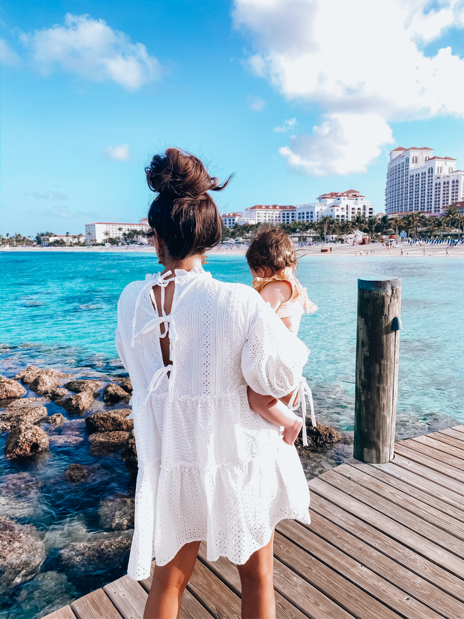 bahamas bahamar water view review | What to Wear in the Bahamas by popular US travel blog, The Sweetest Thing: image of a woman holding her baby girl and wearing a Red Dress On That Note White Eyelet Dress, CULT GAIA Banu Twisted Raffia Clutch, Dior DiorSociety2 Round Beaded Metal Sunglasses, Steve Madden TRAVEL CLEAR, Nordstrom Pillow Talk Lip Cheat Lip Liner CHARLOTTE TILBURY, Nordstrom Hot Lips Lipstick CHARLOTTE TILBURY, Nordstrom Gloss Luxe Moisturizing Lipgloss TOM FORD, Chanel Earrings, Dior and Cartier stack, Rolex watch, Dior Montaigne ring, Amazon Korobeauty Hair Bows, and a Etsy baby polka dot two piece. 