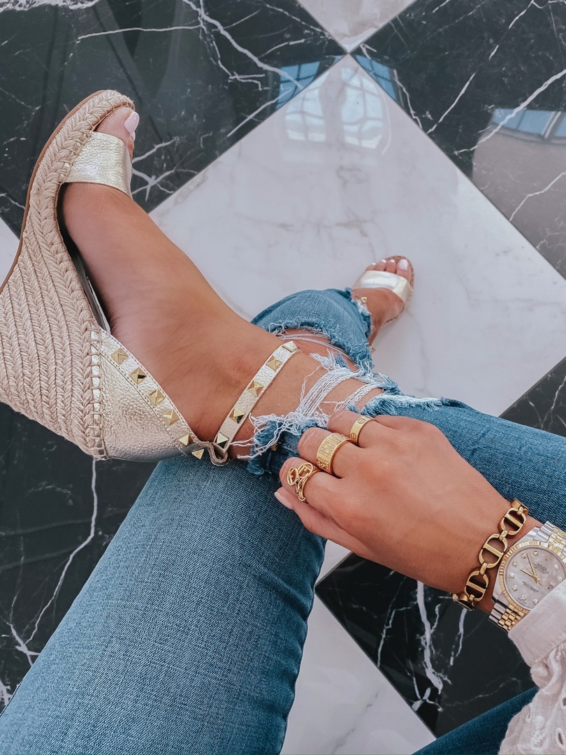 Spring Sales by popular US life and style blog, The Sweetest Thing: image of a woman wearing Good Waist Ripped High Waist Ankle Skinny Jeans GOOD AMERICAN, Cartier bracelet, and Steve Madden MCKENNA GOLD LEATHER wedges. 