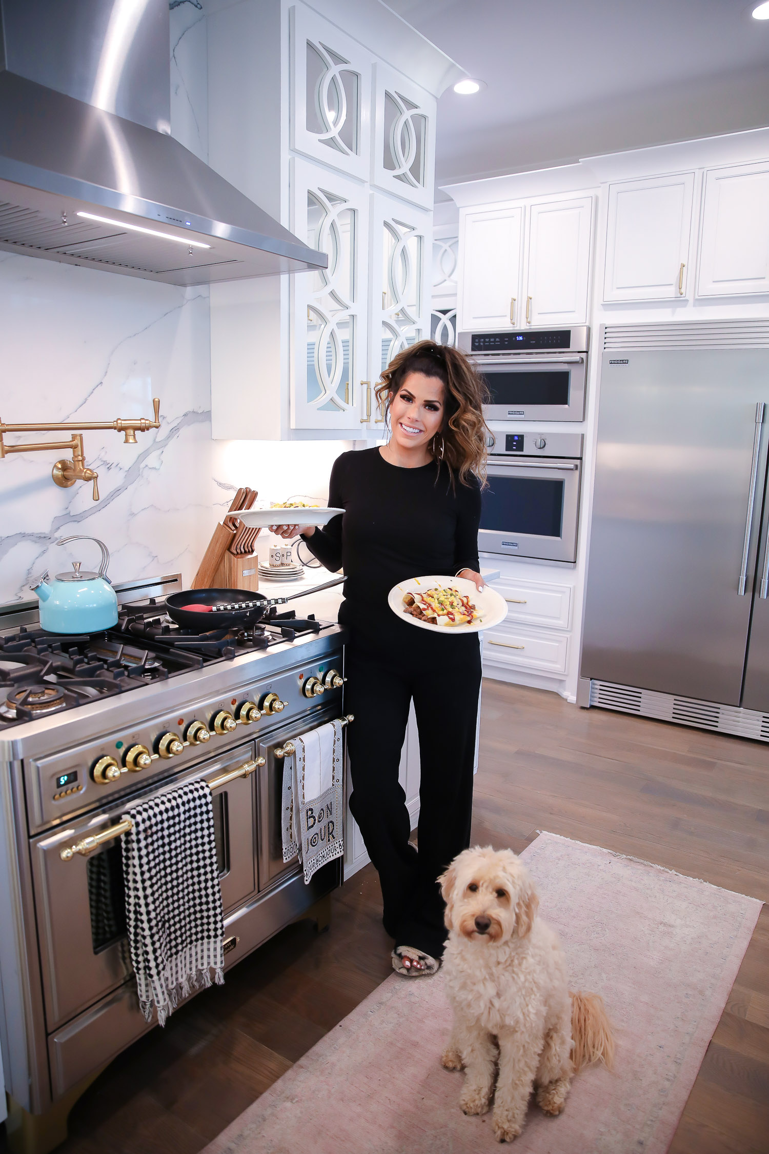 Home Chef review, home chef discount code 2020, emily gemma home chef code 2020, emily ann gemma | BBQ Beef Enchiladas by popular US lifestyle blog, The Sweetest Thing: image of a woman wearing a Verishop LETT Montreal Rib Top and Verishop LETT Heathrow Wide Leg Pant and standing on a pink rug runner in her kitchen and holding two plates of bbq beef enchiladas.