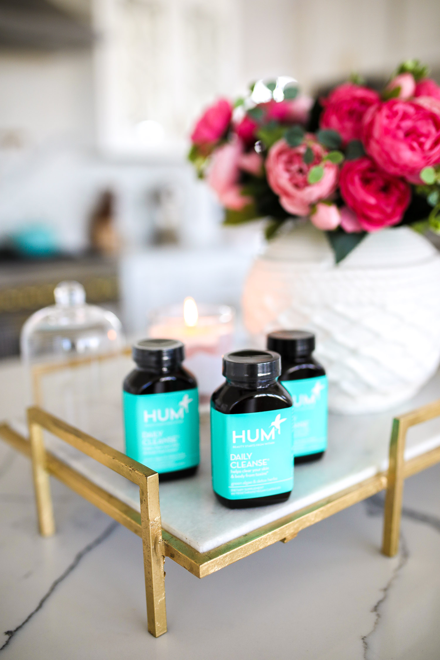 hum nutrition daily cleanse supplements, skin clearing vitamins, green algae vitamins, emily gemma skincare routine | Hum Daily Cleanse by popular US lifestyle blog, The Sweetest Thing: image of 3 bottle of Hum Daily Cleanse supplement bottles next to a white ceramic vase with pink roses in it. 