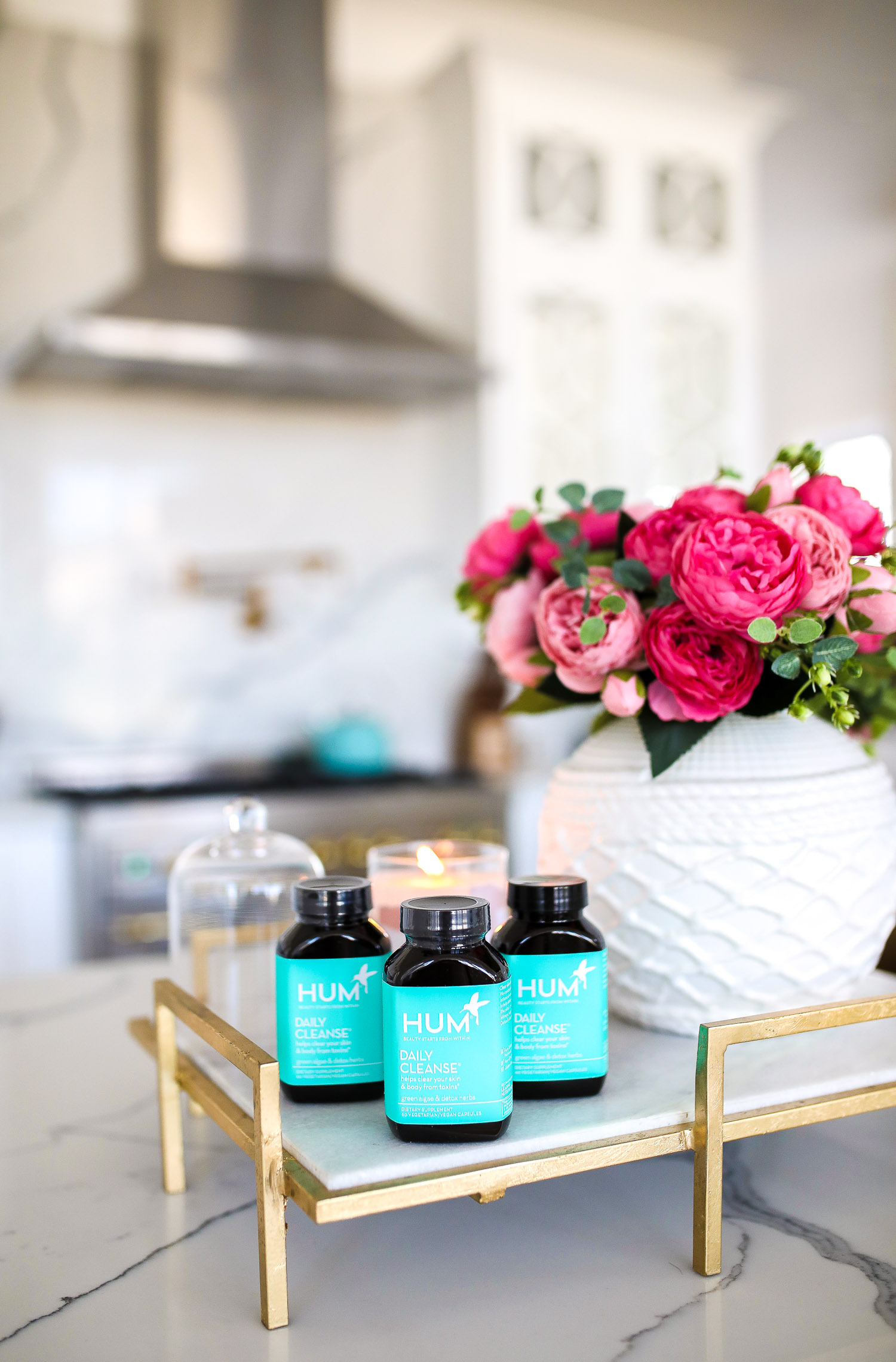 hum nutrition daily cleanse supplements, skin clearing vitamins, green algae vitamins, emily gemma skincare routine | Hum Daily Cleanse by popular US lifestyle blog, The Sweetest Thing: image of three bottles of Hum Daily Cleanse supplements next to a white ceramic vase filled with pink roses. 