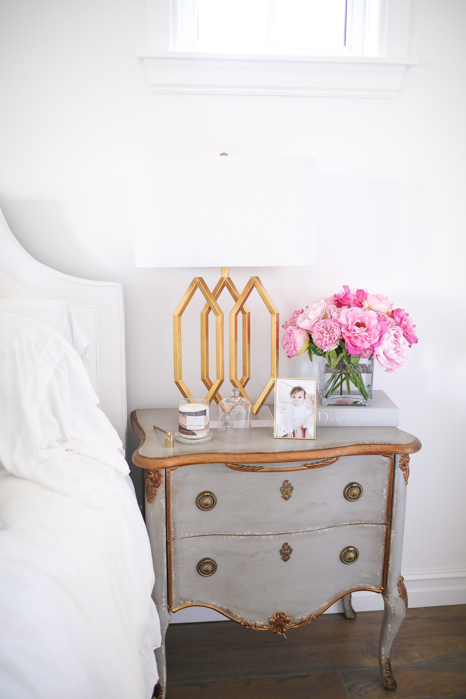 Barefoot dreams blankets, spring gift ideas 2020, commando butter bra reivew, see by chloe wedges, nordstrom must haves spring 2020, emily gemma | Things That Make Me Happy by popular US lifestyle blog, The Sweetest Thing: image of a grey night stand with a gold lamp, gold picture frame, candle, and vase of pink flowers on top. 
