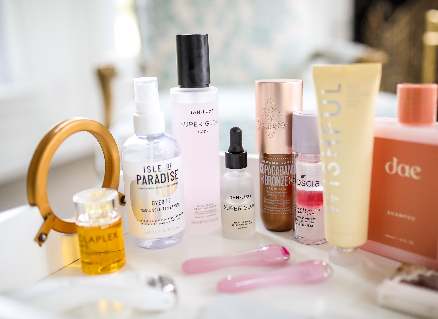 Sephora Haul spring 2020, best sephora products skincare spring 2020, DAE haircare review, Huda Beauty Wishful scrub review, sephora VIB event spring 2020 | Self Care Products by popular US life and style blog, The Sweetest Thing: image of a woman sitting in a arm chair next to a white enamel tray filled with Dae hair products, fake eye lashes, Amika flash instant shine mask, Wisheful Yo Glow, Tan Luxe Super Glow, and Olaplex.
