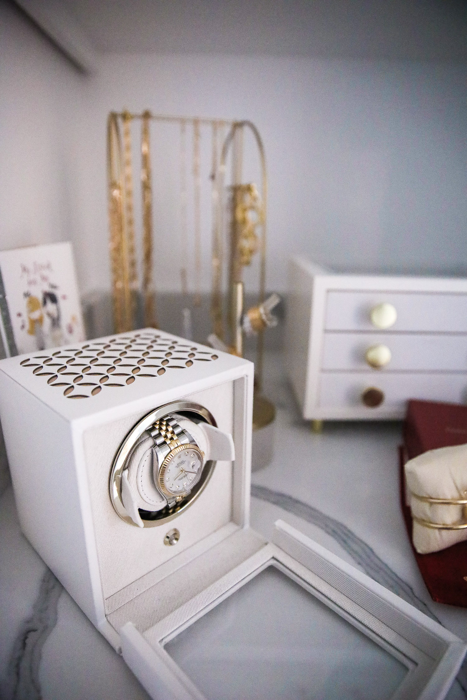 rolex watch winder, white wolf Rolex watch winder, Emily Gemma | Nighttime Routine by popular US beauty blog, The Sweetest Thing: image of a watch winder box, white jewelry box, and gold jewelry rack. 