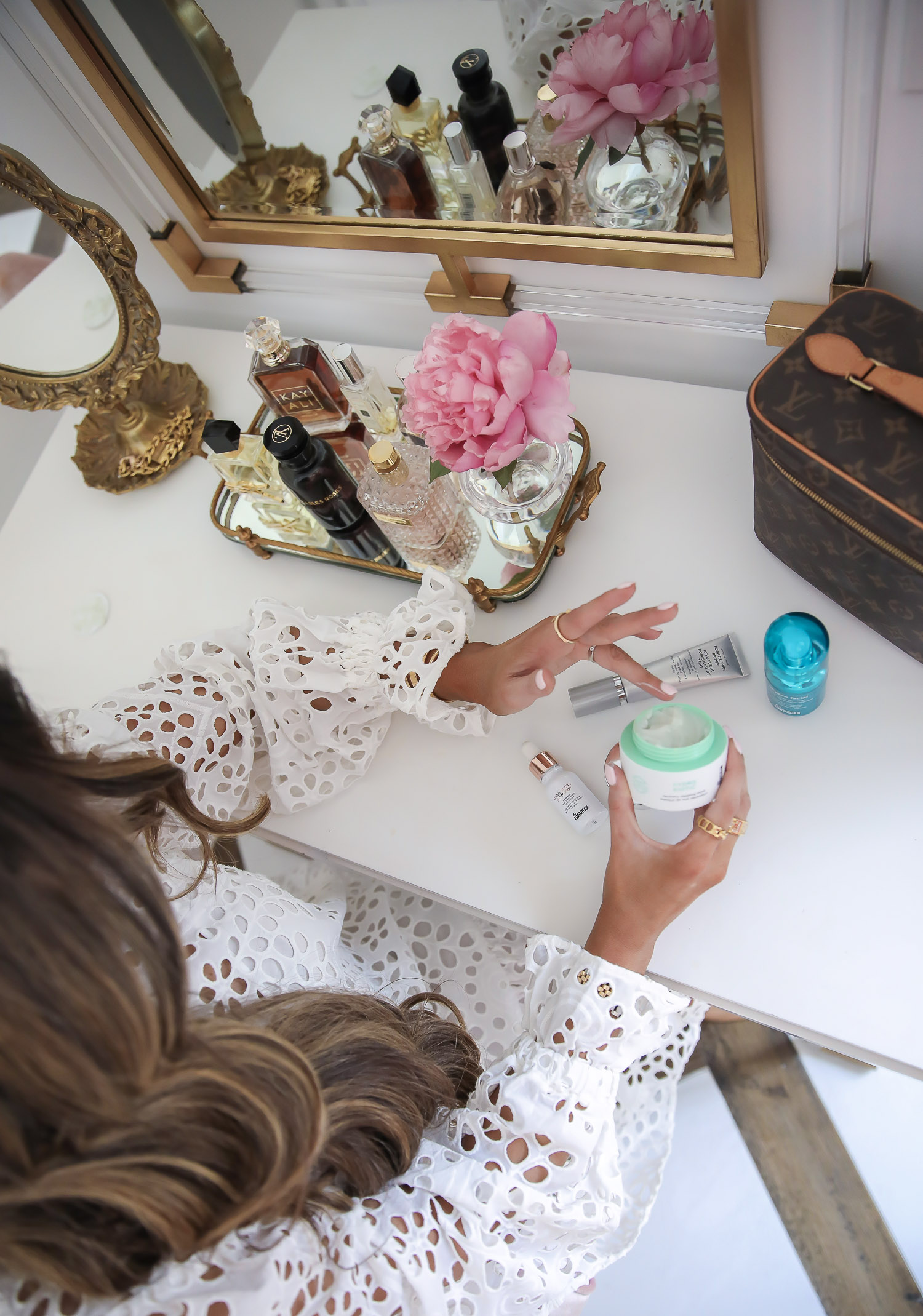 Dr Brandt Pore Refiner Primer by popular US beauty blog, The Sweetest Thing: image of Emily Gemma wearing a H & M Eyelet Embroidery Dress and holding a bottle of Dr Brandt Hydro Biotic while sitting at her vanity. 