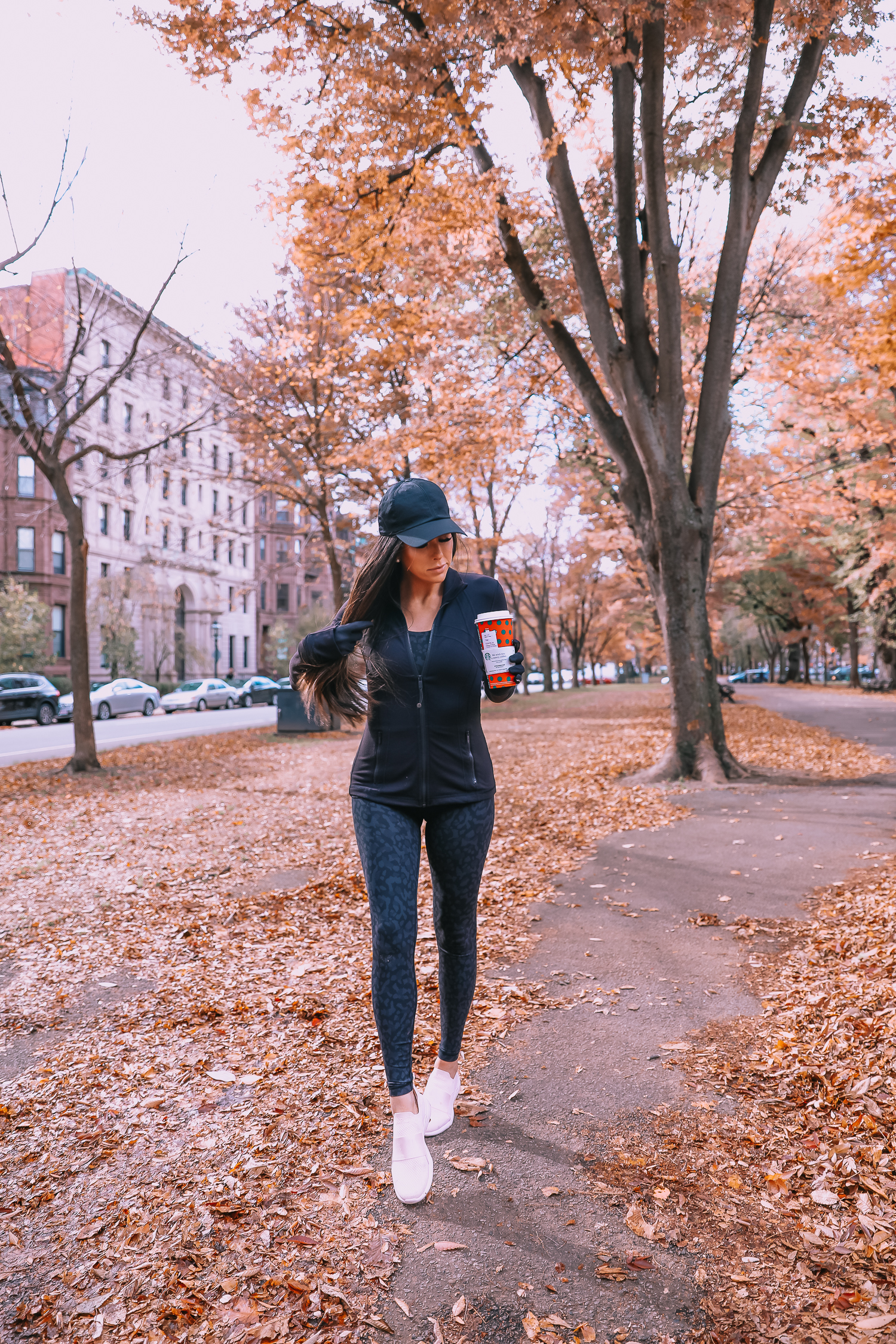 best Lululemon leggings, most flattering Lululemon leggings, Emily Ann Gemma | Cute Workout Clothes by popular US fashion blog, The Sweetest Thing: image of Emily Gemma walking outside and wearing a Lululemon jacket, Lululemon leggings, Lululemon sports bra, Lululemon tank, Lululemon cap, Lululemon gloves, and holding a Starbucks cup. 