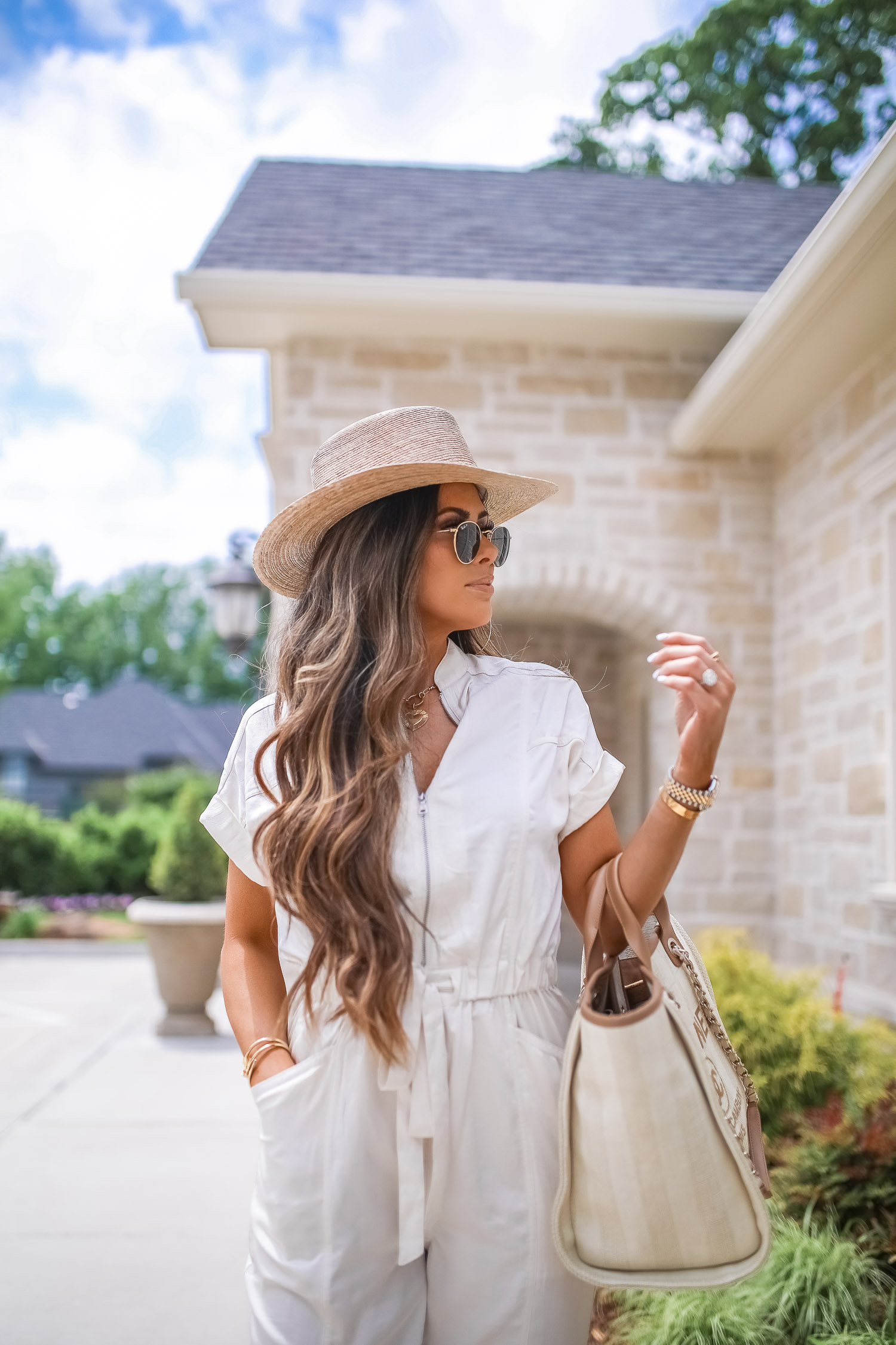 Off White Jumpsuit by popular US fashion blog, The Sweetest Thing: image of a woman wearing a Express Zip Front Utility Jumpsuit, Nordstrom heeled sandals, Express Large Metal Hoop Earrings, Cartier jewelry, a straw hat, and holding a Chanel bag. 