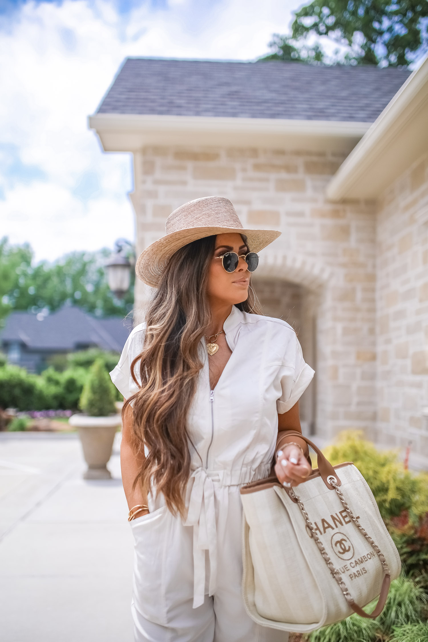 Off White Jumpsuit by popular US fashion blog, The Sweetest Thing: image of a woman wearing a Express Zip Front Utility Jumpsuit, Nordstrom heeled sandals, Express Large Metal Hoop Earrings, Cartier jewelry, a straw hat, and holding a Chanel bag. 