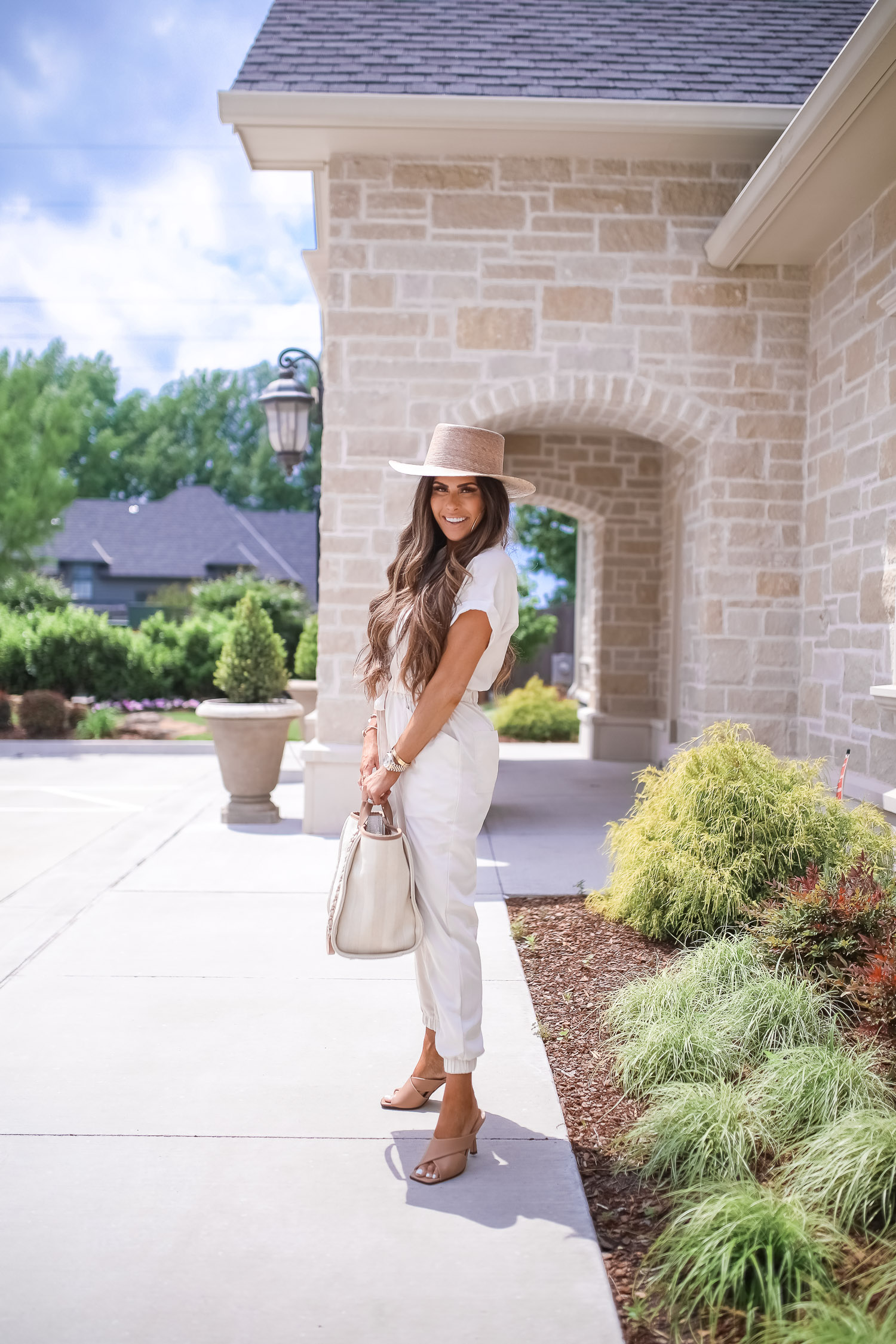 Off White Jumpsuit by popular US fashion blog, The Sweetest Thing: image of a woman wearing a Express Zip Front Utility Jumpsuit, Nordstrom heeled sandals, Express Large Metal Hoop Earrings, Cartier jewelry, a straw hat, and holding a Chanel bag. 