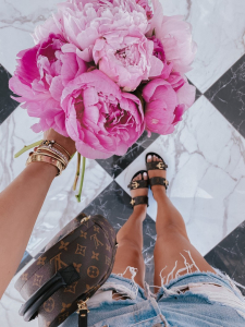 peony inspo, LV slides, spring fashion, jean shorts, black and white flooring, Cartier bracelet stack | Instagram Recap by popular US life and style blog, The Sweetest Thing: image of Emily Gemma holding a bouquet of peonies and wearing a pair of 501® High Waist Cutoff Denim Shorts LEVI'S and Louis Vuitton Palm Springs backpack. 