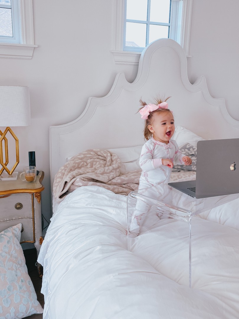 Instagram Recap by popular US life an style blog, The Sweetest Thing: image of a baby girl wearing a pair of Beaufort Bonnet pajamas and standing in front of a Lavish Home acrylic table with a open laptop on it on a bed with a white headboard and white comforter. 