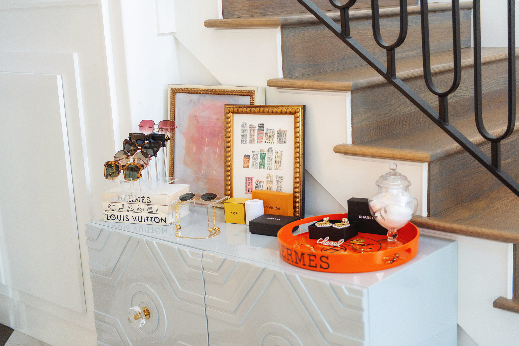 Blog Design by popular US lifestyle blog, The Sweetest Thing: image of a grey enamel dresser with an acrylic sunglasses display, Hermes tray, artwork in gold frames, and Chanel jewelry. 