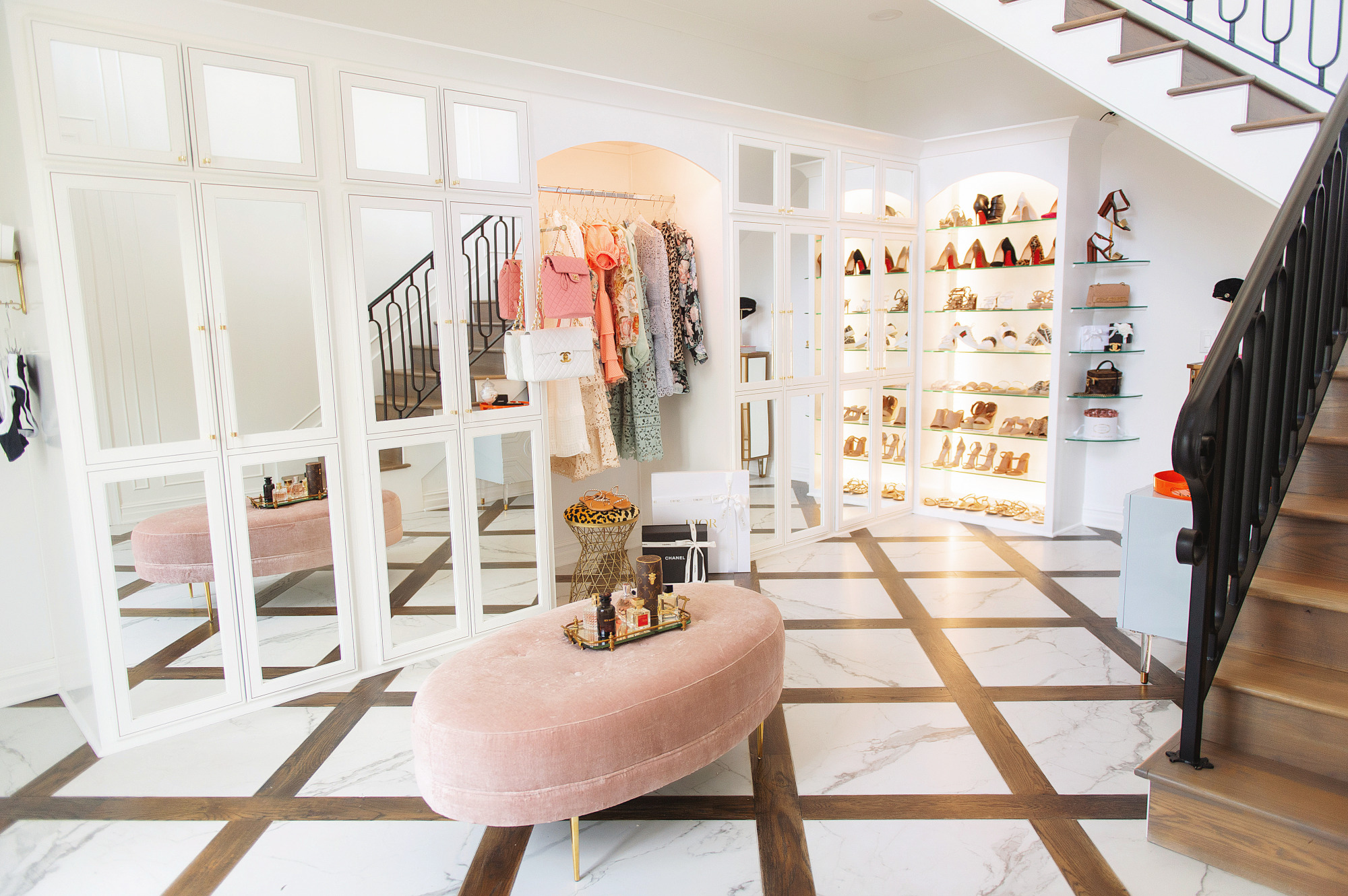 Blog Design by popular US lifestyle blog, The Sweetest Thing: image of a two story closet filled with a tufted pink velvet bench, shoe display and clothing rack filled with designer dresses. 