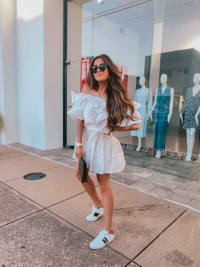  Instagram Recap by popular US life an style blog, The Sweetest Thing: image of Emily Gemma standing in front of a storefront window and wearing a Nasty Gal white off the shoulder dress, Gucci sneakers, Chloe necklace, Natalie B. earrings, Saint Laurent sunglasses, and Chan Luu anklet. 