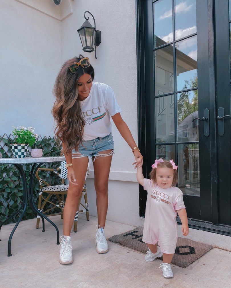 Instagram Recap by popular US life an style blog, The Sweetest Thing: image of Emily Gemma standing outside with her daughter Sophie and wearing a Gucci t-shirt, Gucci onesie, cutoff denim shorts, Reebok shoes, and Urban Outfitters sunglasses. 