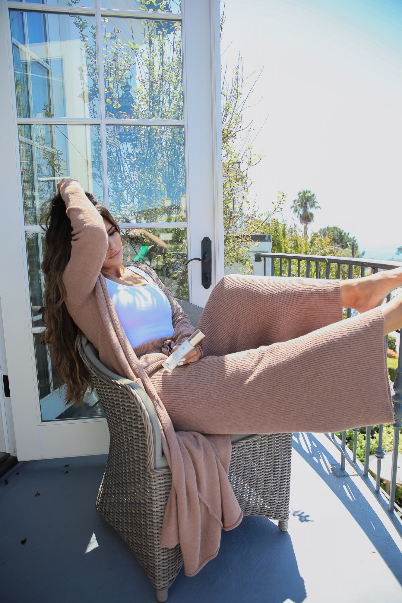 skinceuticals neck cream tripeptide-r neck repair, best neck cream for wrinkles crepes, best skincare product for neck, emily ann gemma,_ | Skincare Product by popular US beauty blog, The Sweetest Thing: image of Emily Gemma sitting outside on a balcony and holding a bottle of Skinceuticals Tripeptide-R Neck Repair. 