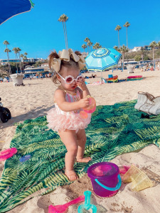 summer fashion 2020, swimsuit outfits, beach outfits, Emily Ann Gemma, Baby swimsuits |Instagram Recap by popular US life and style blog, The Sweetest Thing: image of a baby girl standing in the sand at the beach and wearing daisy frame sunglasses and a Maisonette swimsuit. 