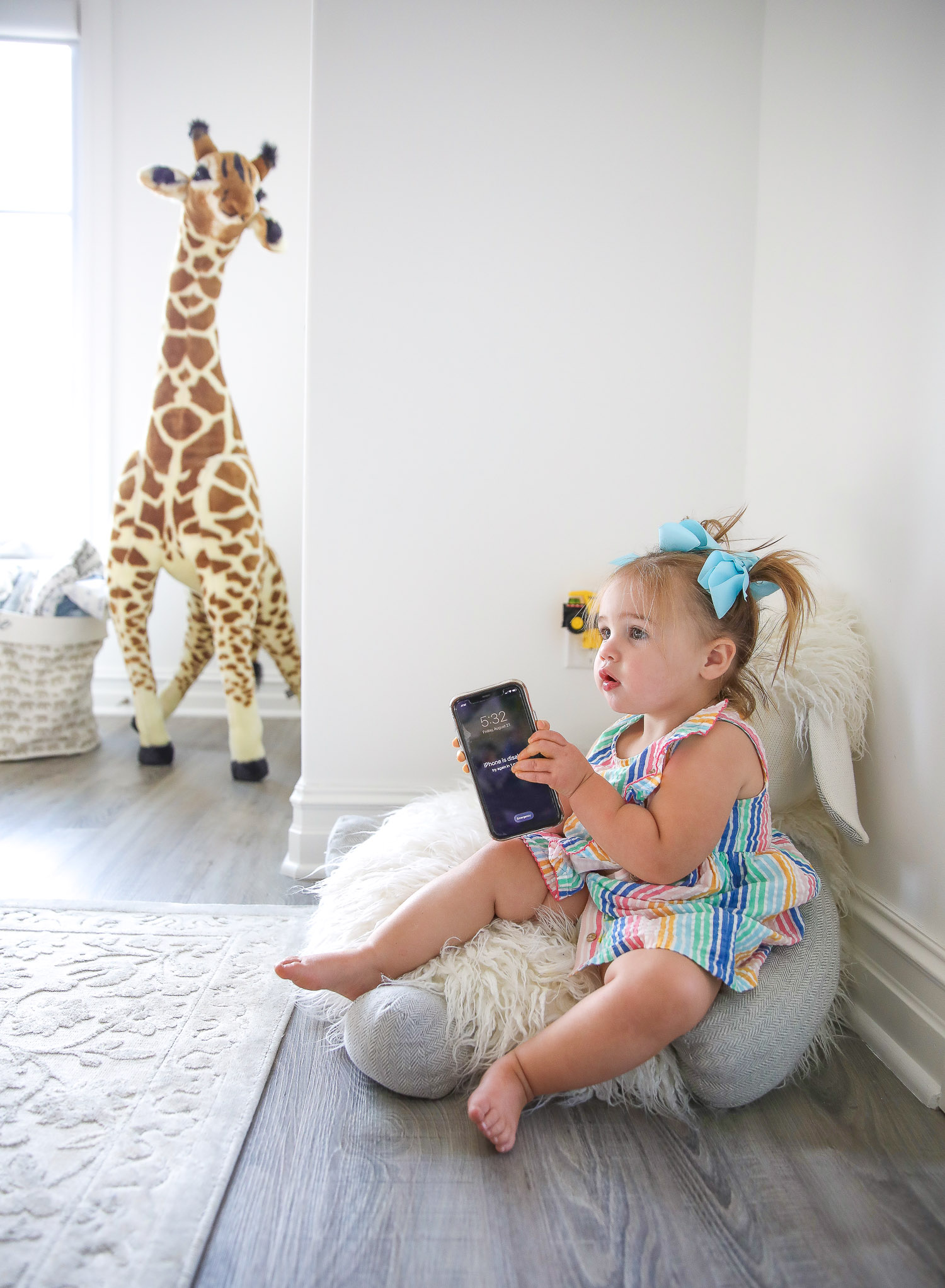 walmart kids home organization must haves, playroom organization ideas, emily gemma, the sweetest thing blog | Playroom Organization by popular US life and style blog, The Sweetest Thing: image of a little girl sitting on a floor pillow and holding a smartphone. 