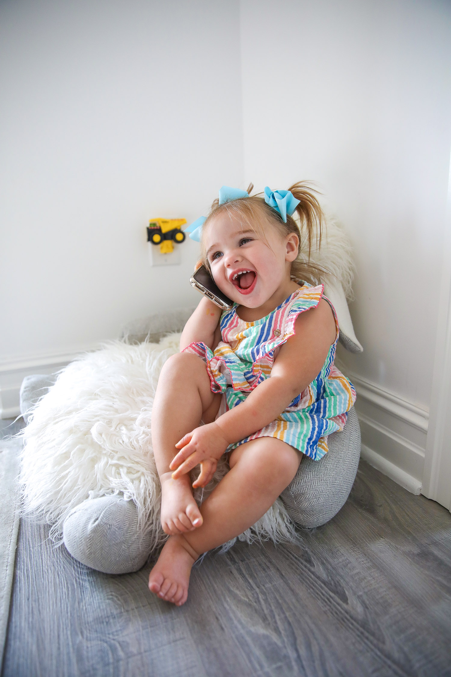 walmart kids home organization must haves, playroom organization ideas, emily gemma, the sweetest thing blog | Playroom Organization by popular US life and style blog, The Sweetest Thing: image of a little girl sitting on a floor pillow and holding a smartphone. 