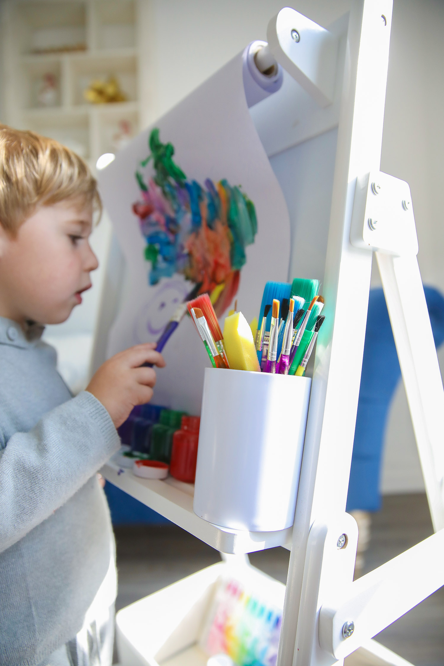 walmart kids home organization must haves, playroom organization ideas, emily gemma, the sweetest thing blog | Playroom Organization by popular US life and style blog, The Sweetest Thing: image of a little boy painting on a Walmart Delta Children Classic Kids Whiteboard/Dry Erase Easel with Paper Roll and Storage with Walmart Go Create Assorted Paint Brushes and Walmart Cra-Z-Art Washable Kids Paint.