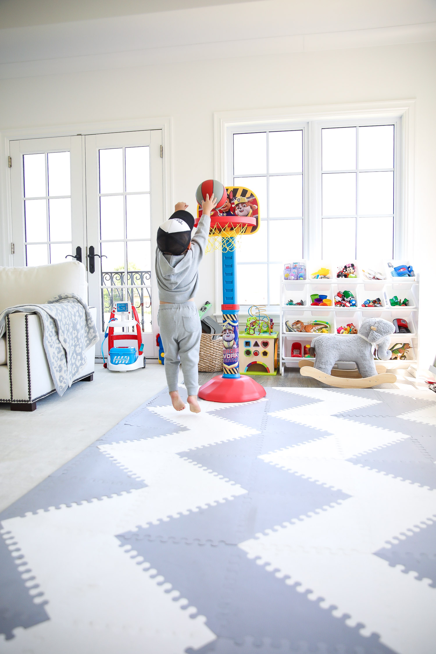 walmart kids home organization must haves, playroom organization ideas, emily gemma, the sweetest thing blog | Playroom Organization by popular US life and style blog, The Sweetest Thing: image of a playroom set up with a Walmart Humble Crew Super-Sized Toy Organizer with 16 Plastic Bins, foam flooring, basketball hoop, and rocking elephant. 